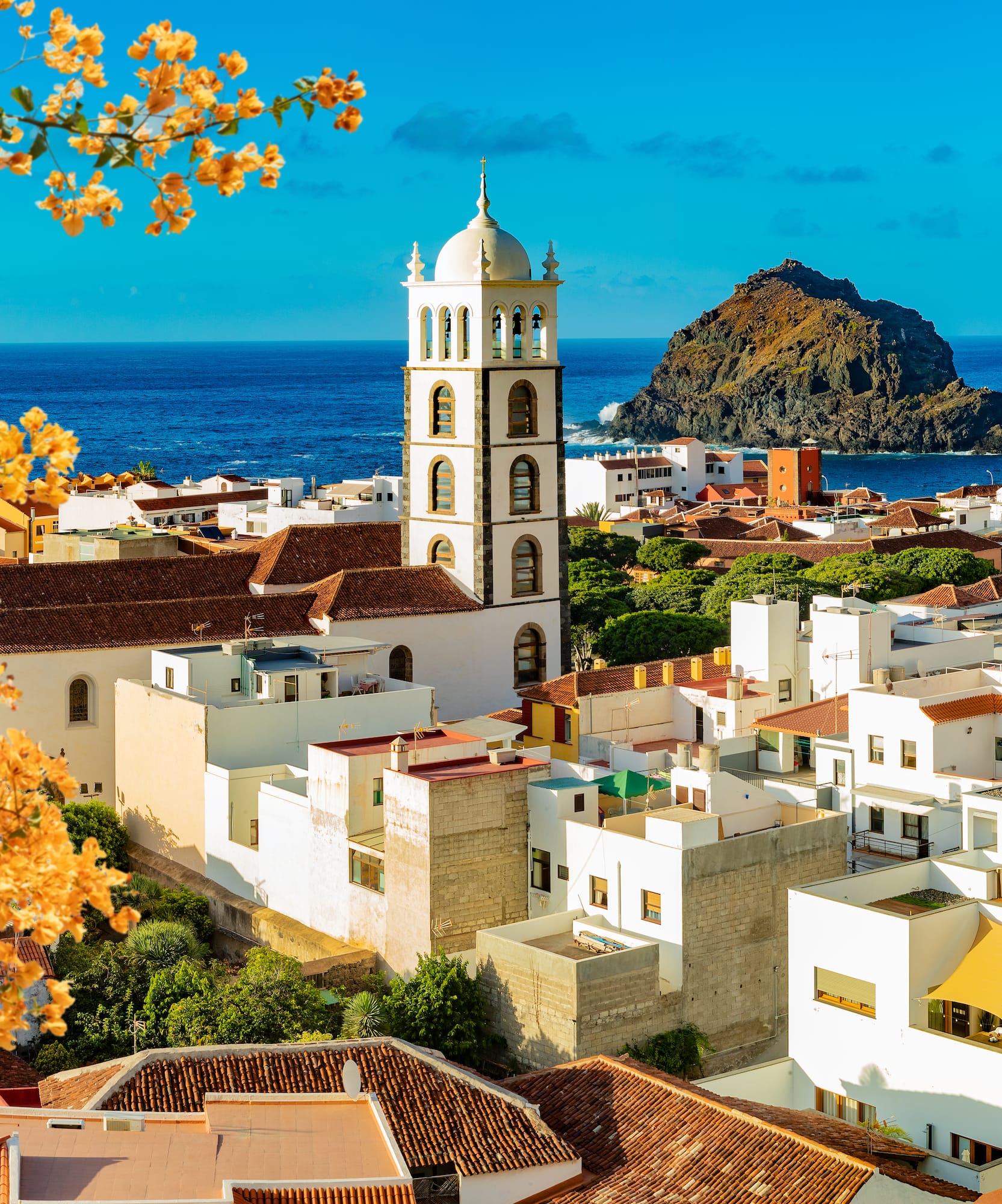a white buildings with a tower and a rock in the background