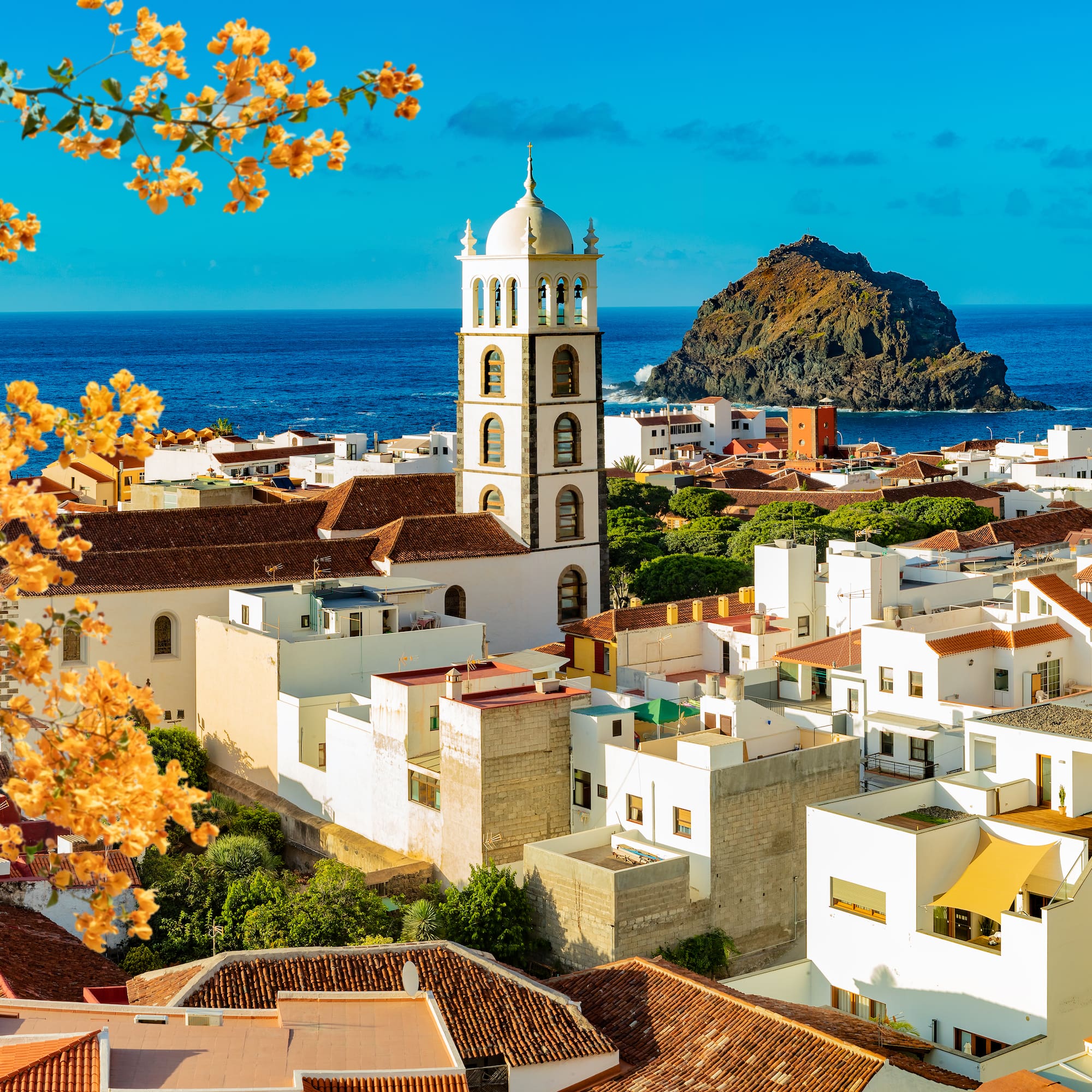 a white buildings with a tower and a rock in the background