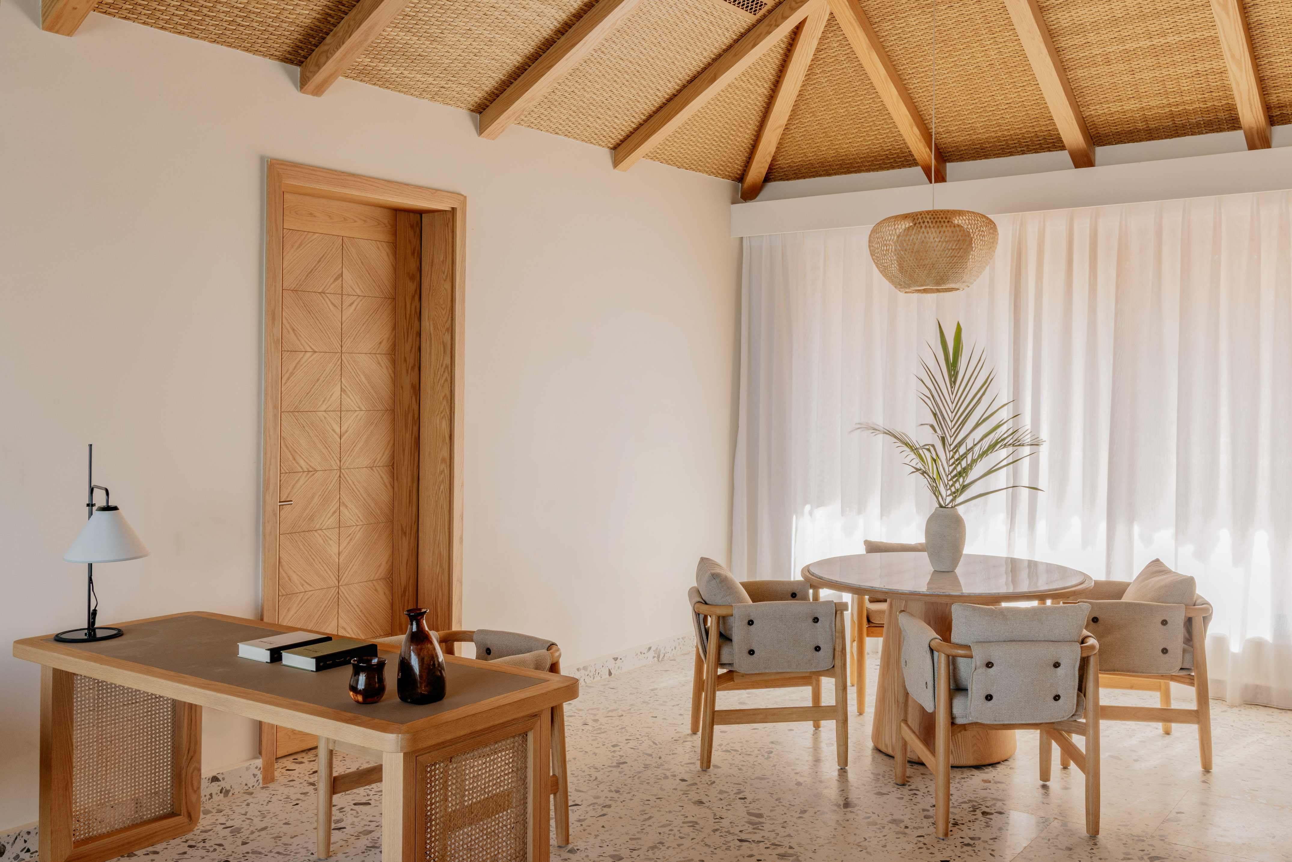 Bright tropical interior with rattan ceiling, wood desk, dining set.