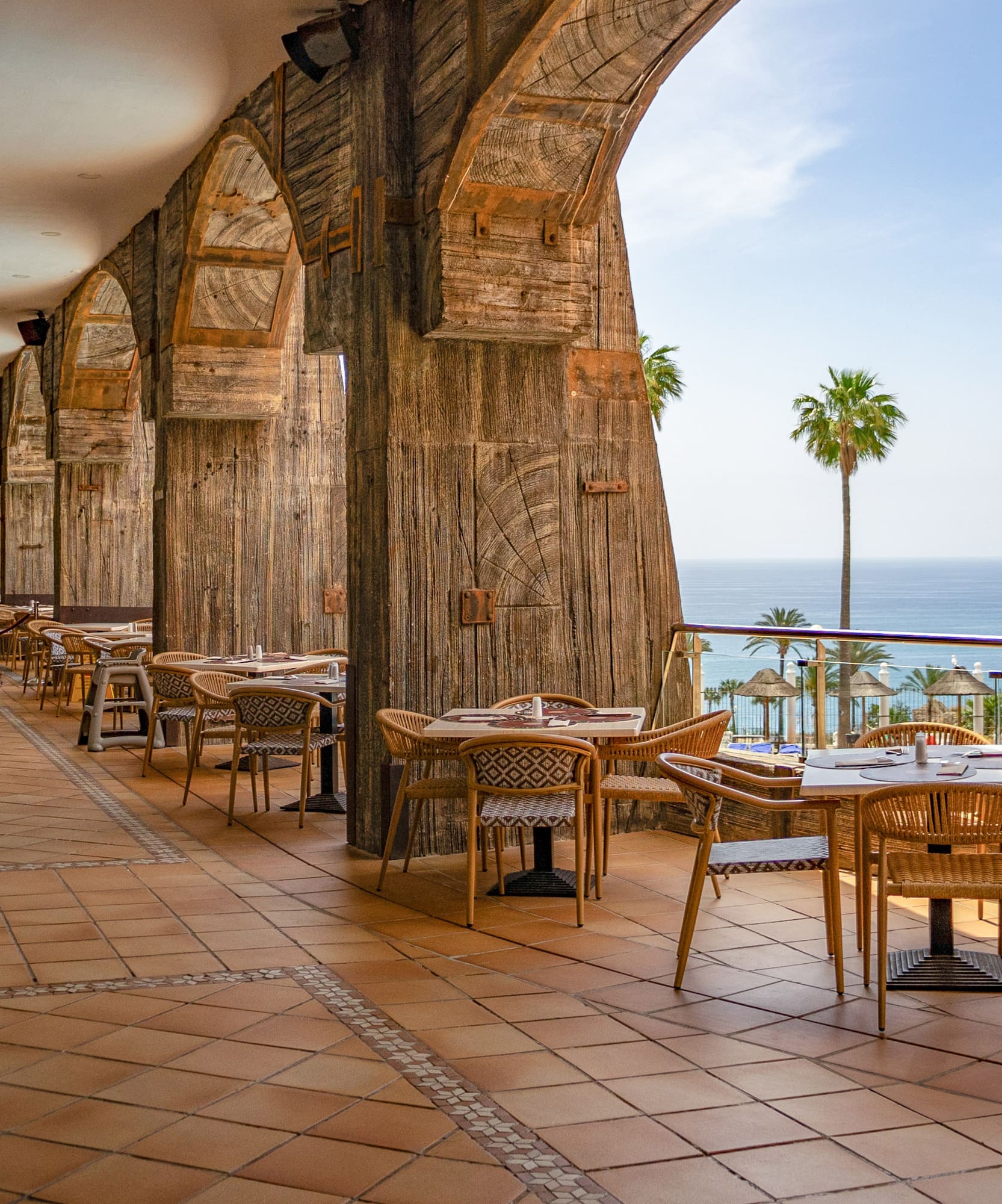a restaurant with tables and chairs on a patio overlooking the ocean