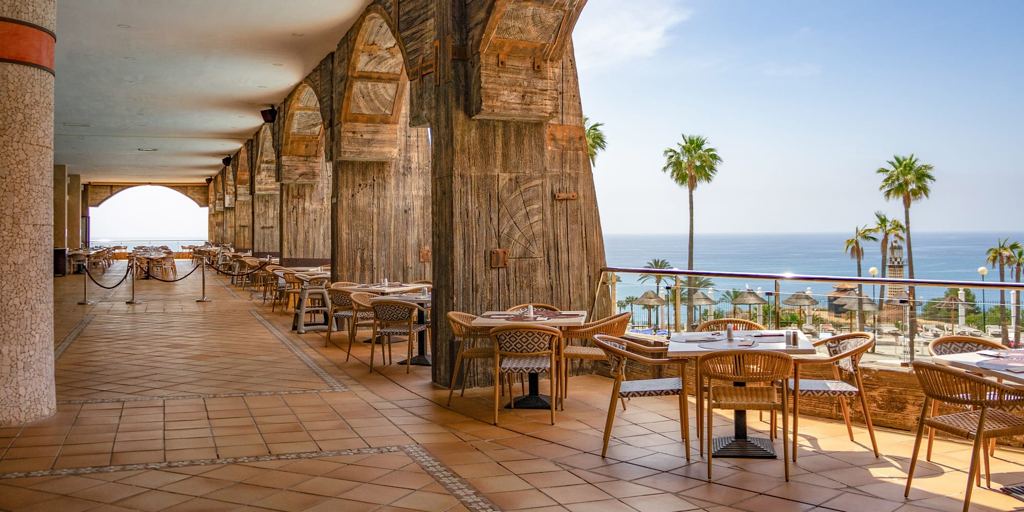 a restaurant with tables and chairs on a patio overlooking the ocean