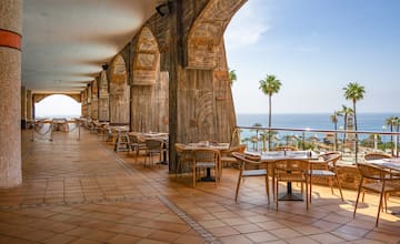 a restaurant with tables and chairs on a patio overlooking the ocean