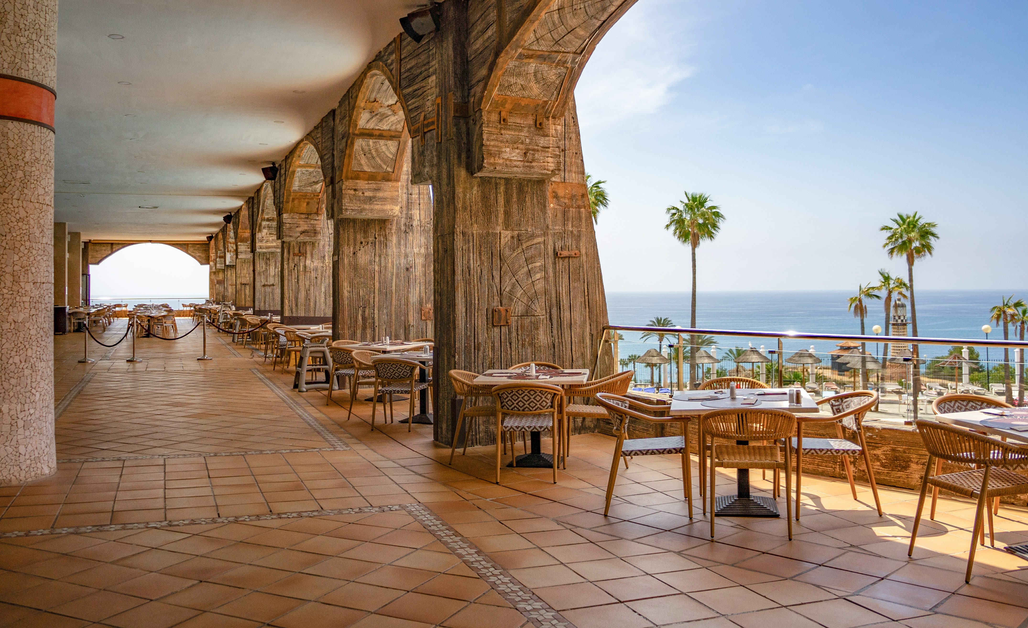 a restaurant with tables and chairs on a patio overlooking the ocean
