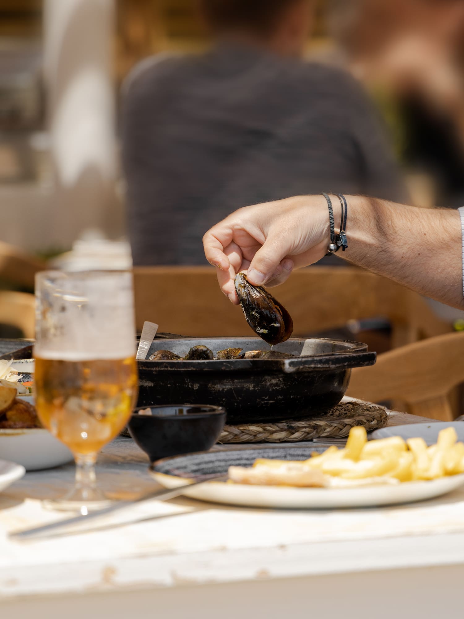 a person holding a clam over a pan of food