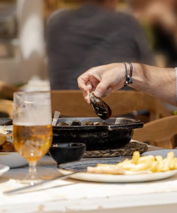 a person holding a clam over a pan of food