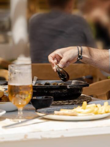 a person holding a clam over a pan of food