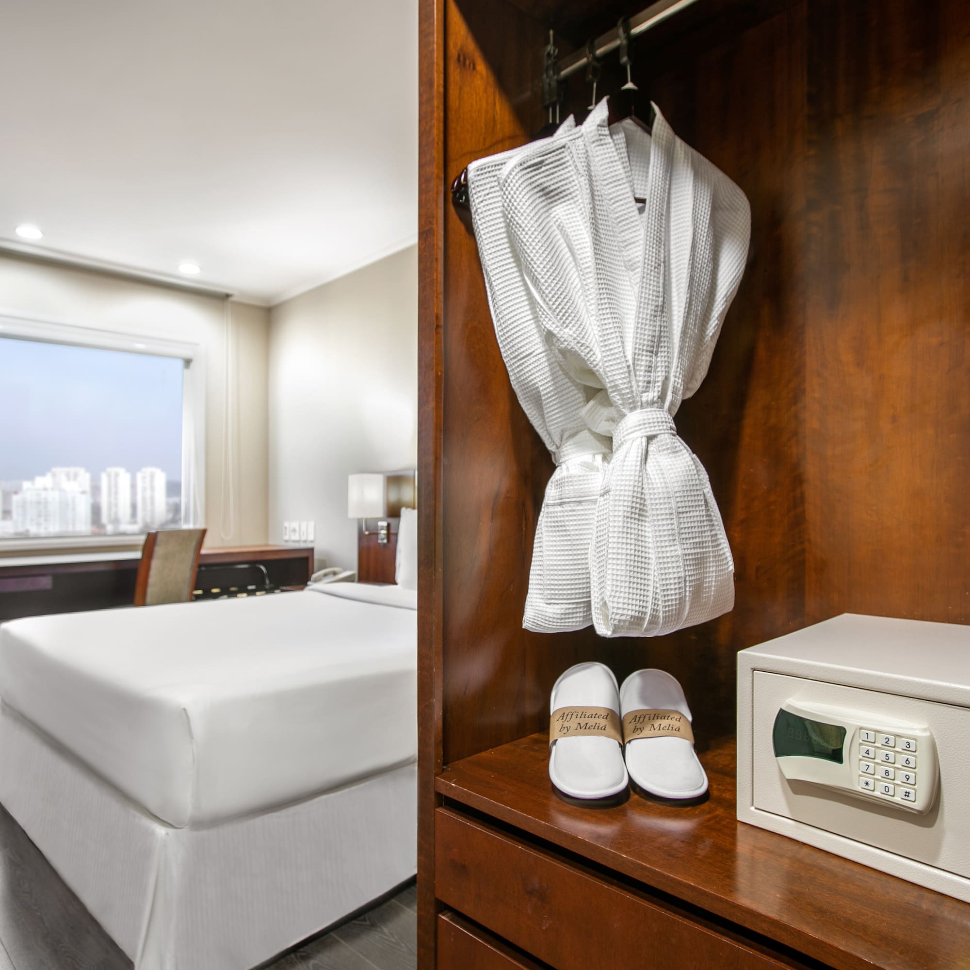 a white robe and slippers on a shelf in a hotel room