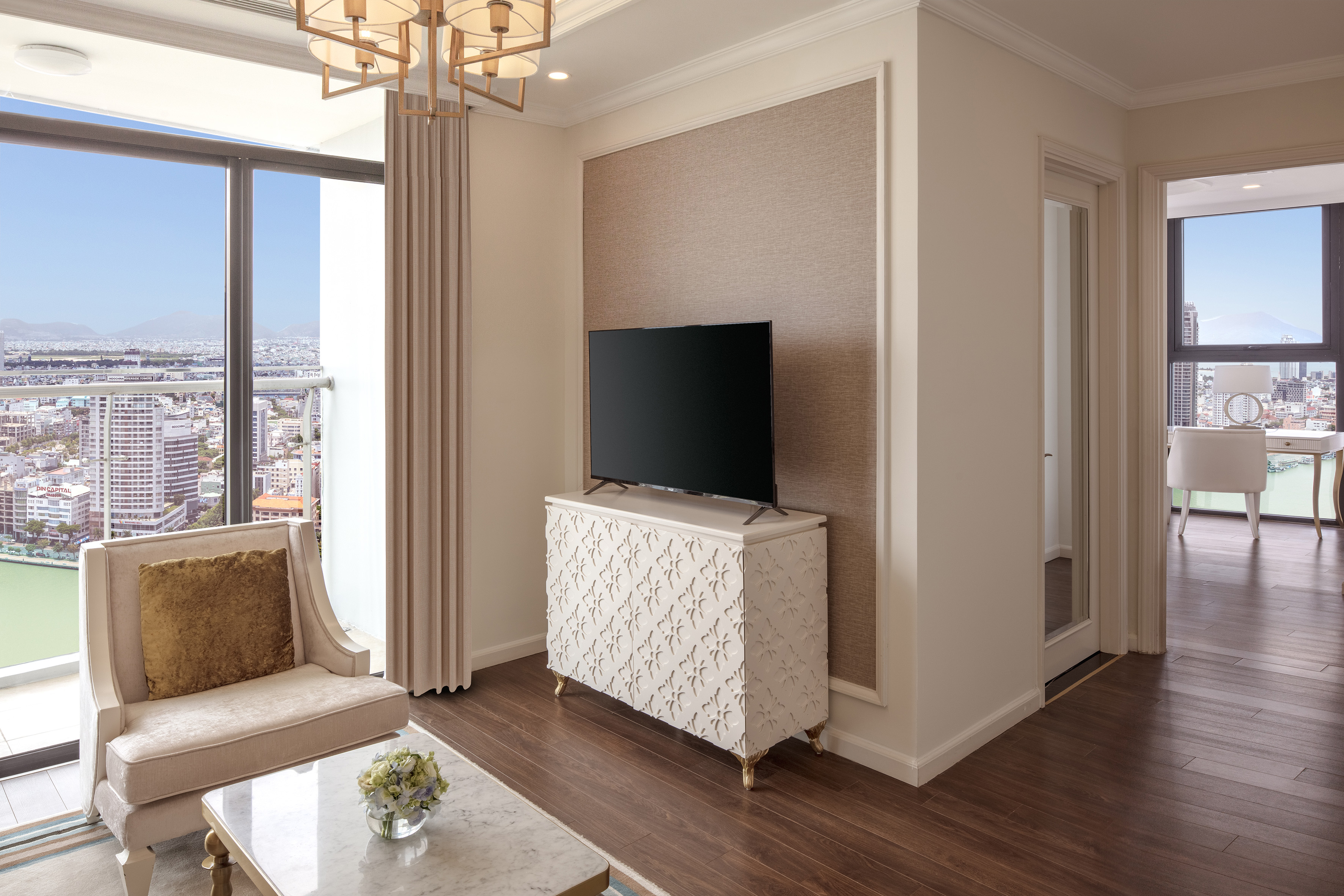 Luxury living room with panoramic city view, TV, and stylish furniture.