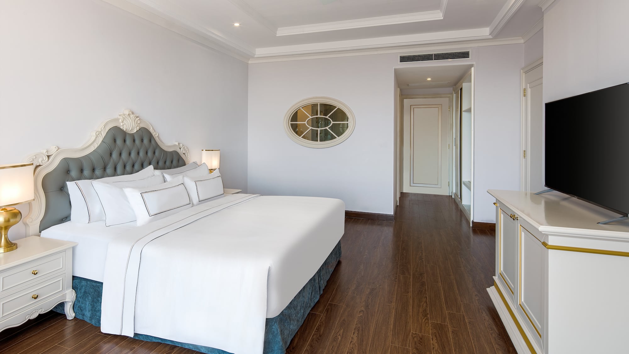 a bedroom with a white bed and wood floor