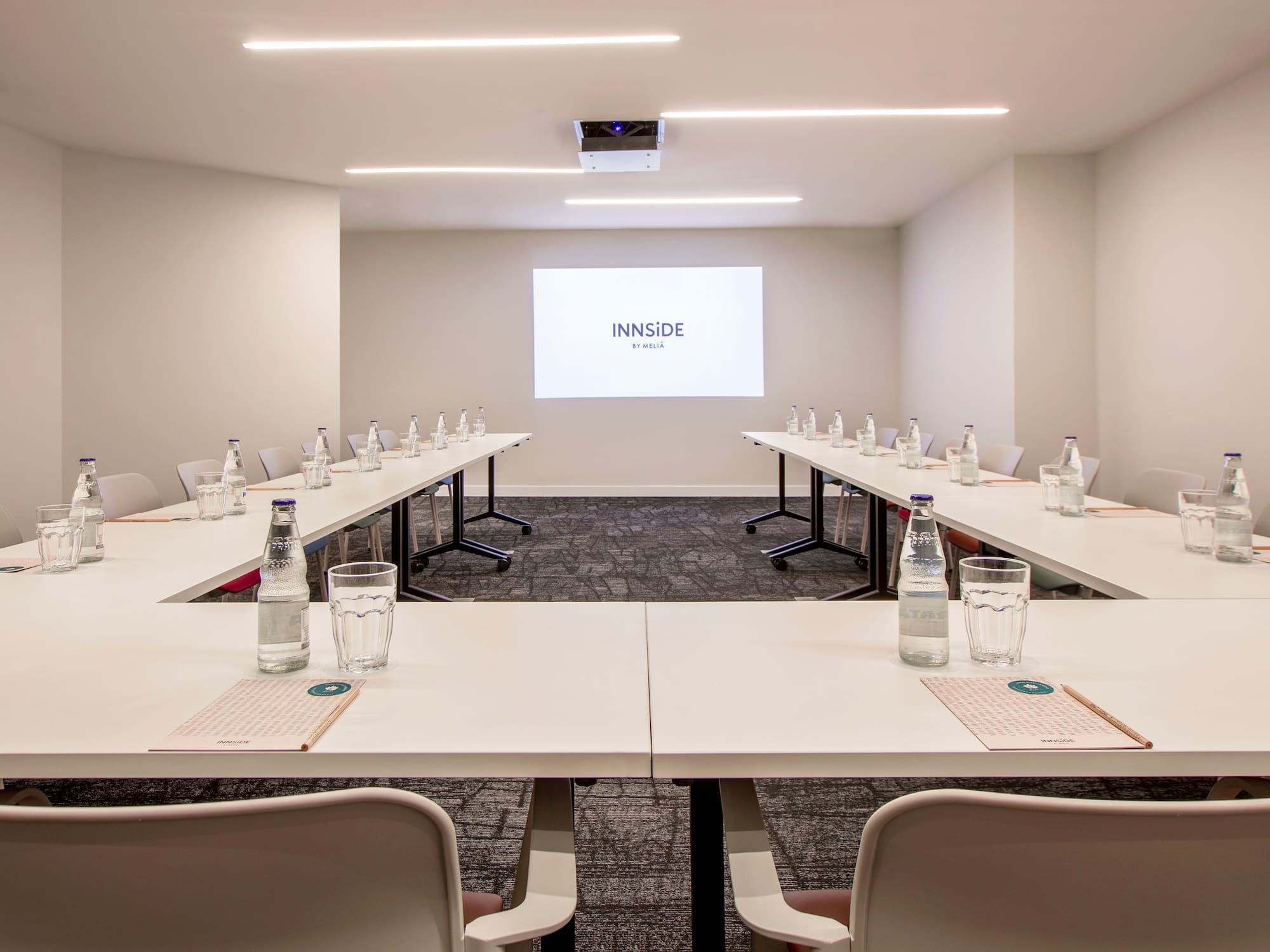 a room with tables and chairs and a projector screen
