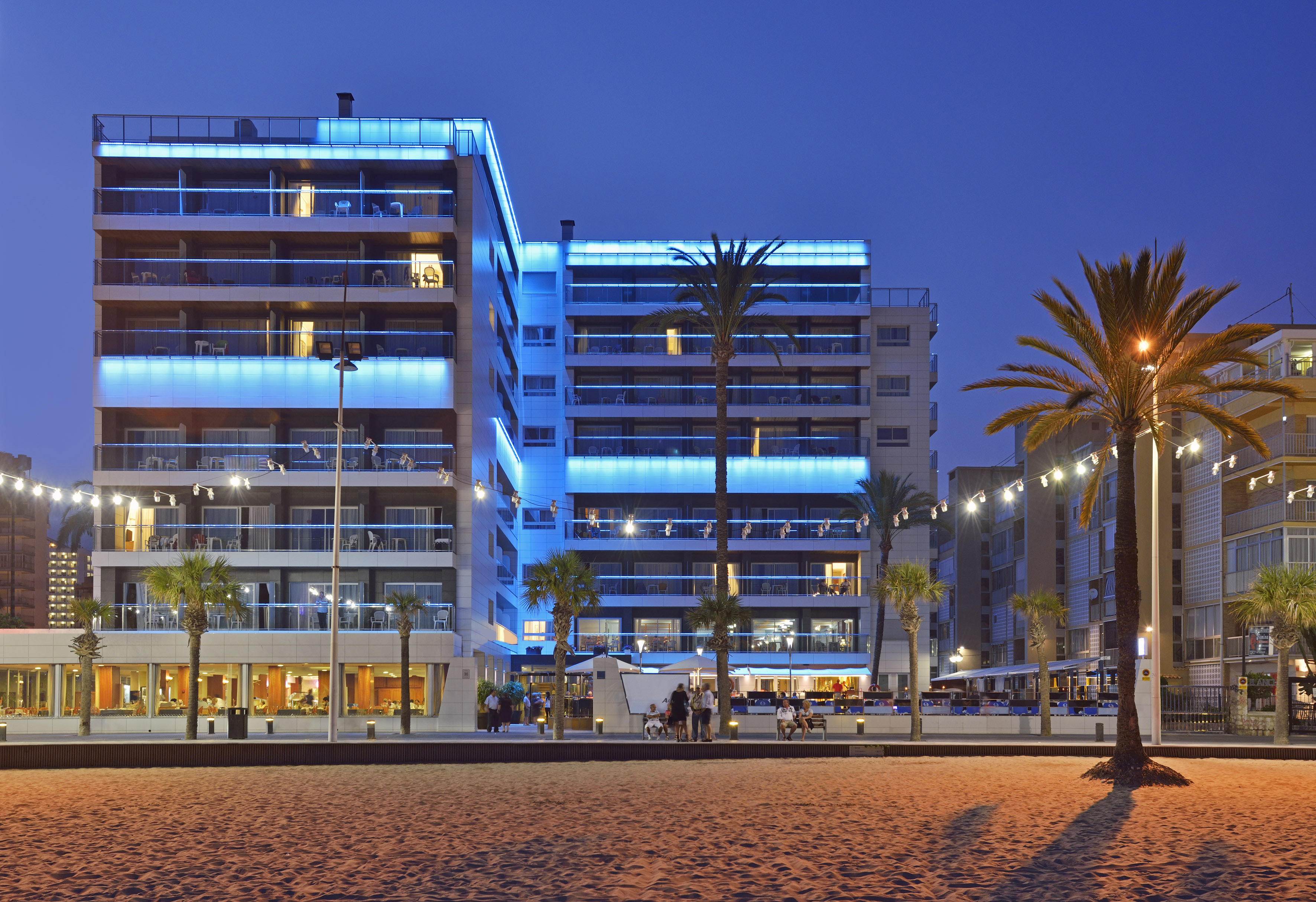 a building with palm trees and people on the beach