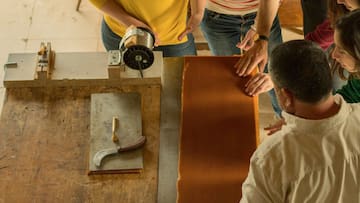 a group of people working on a piece of wood