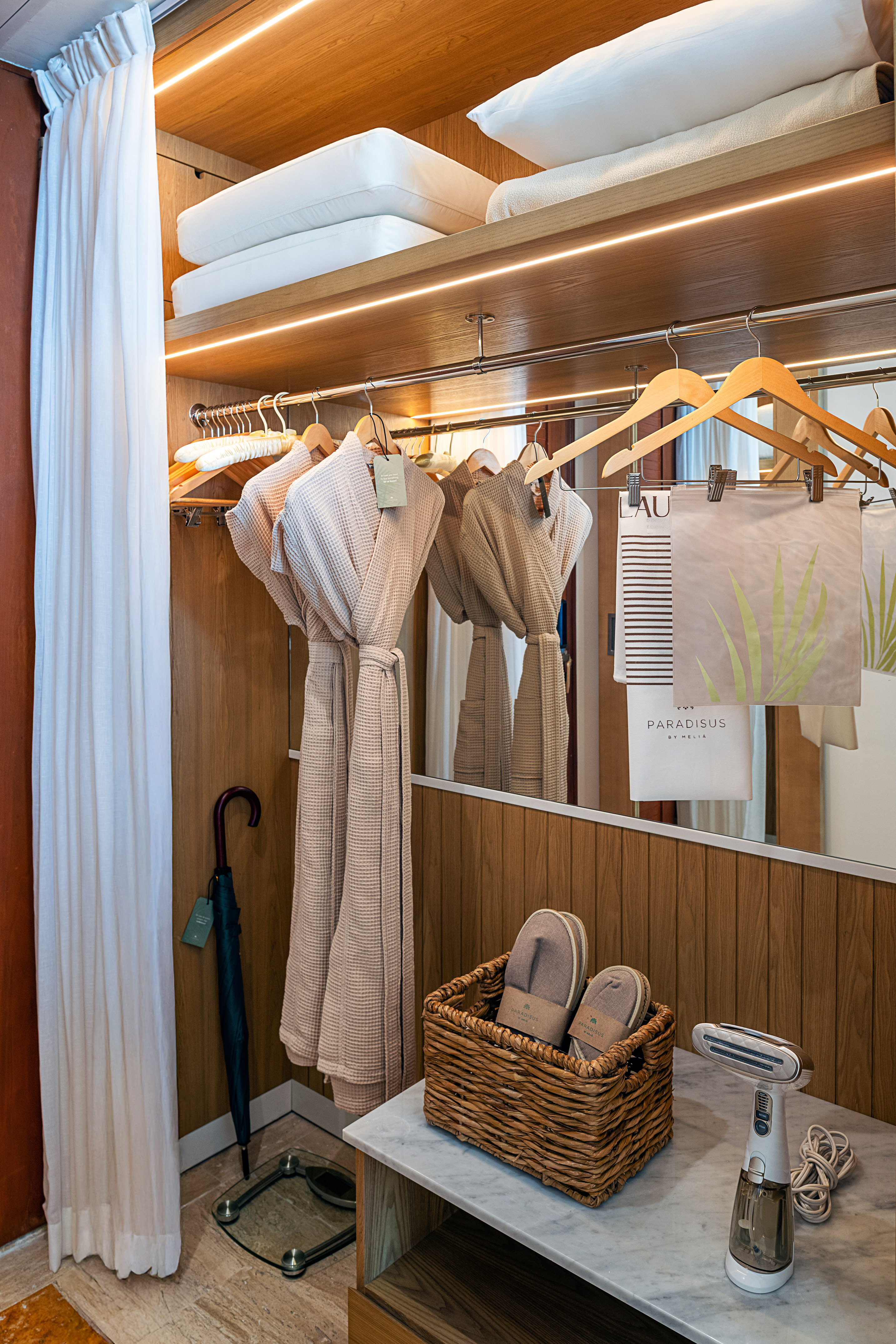 Luxury hotel closet with robes, slippers, pillows, steamer, and Paradisus branding.