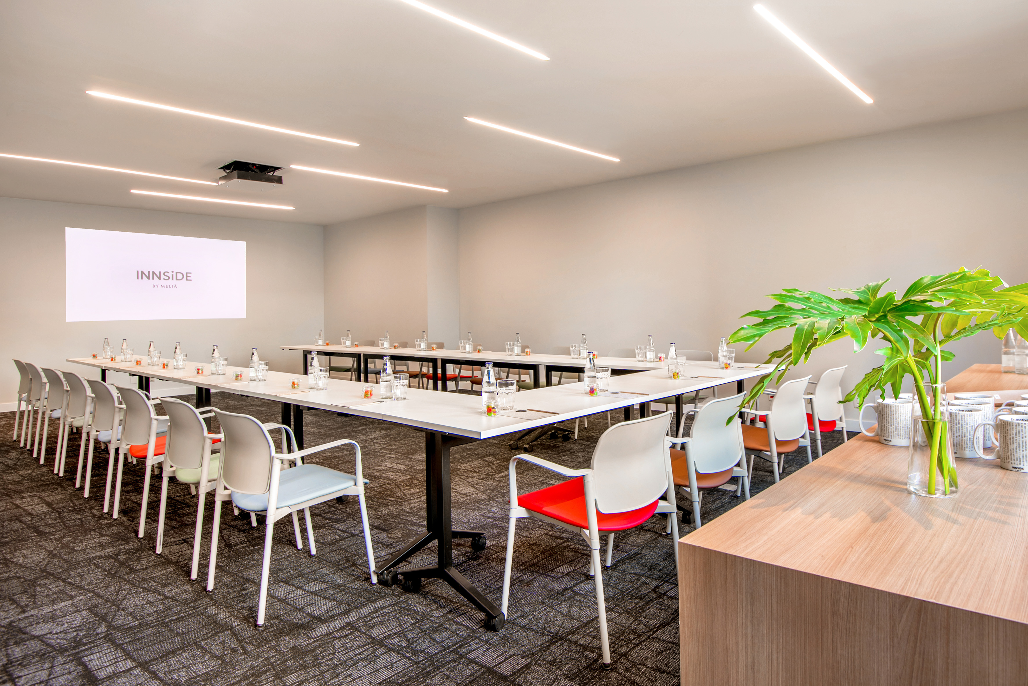 Modern INNSiDE conference room, U-shaped table, projector, colorful chairs.