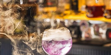 a glass with purple liquid and smoke coming out of it