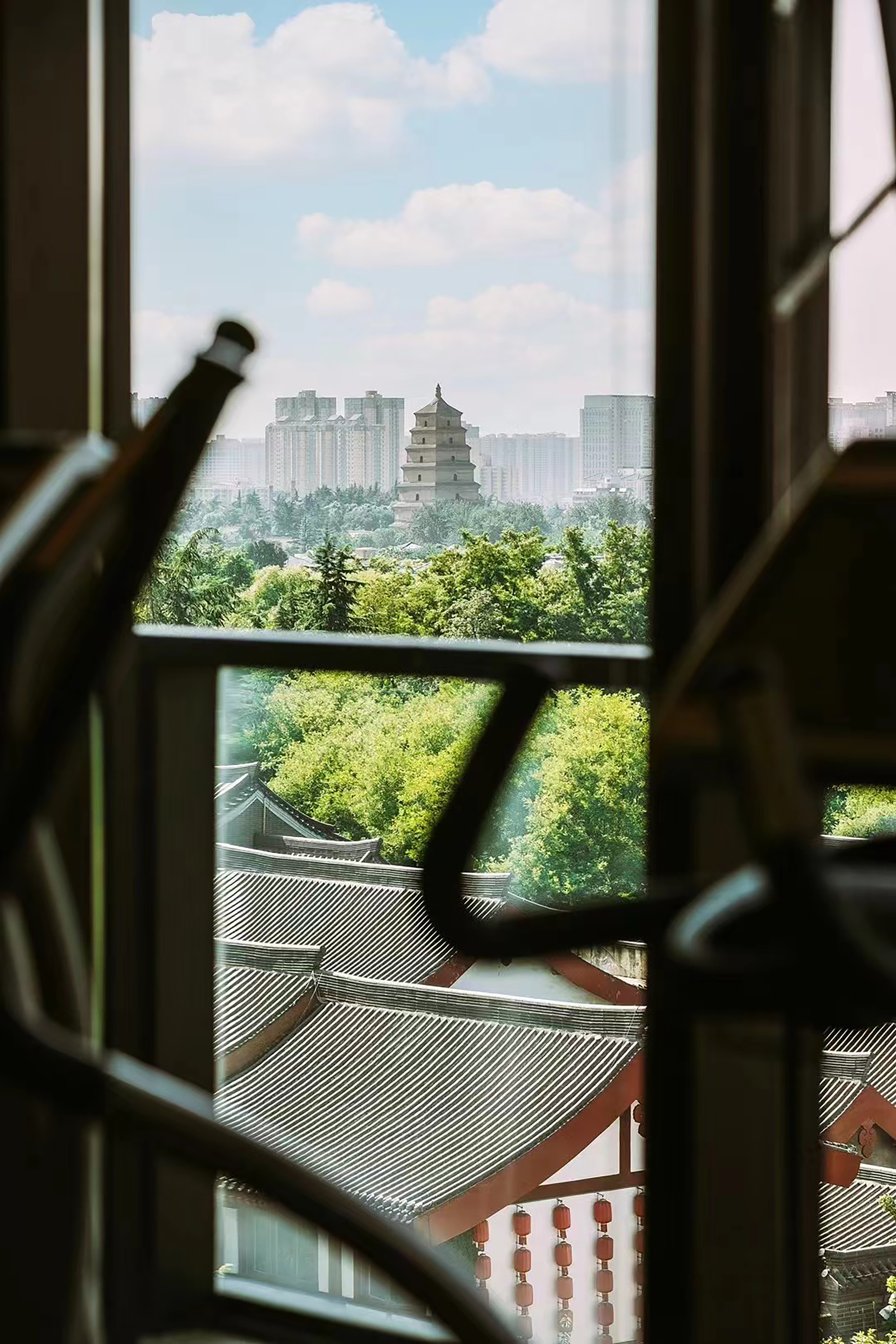 View from window: Chinese pagoda, traditional roofs, modern city skyline.
