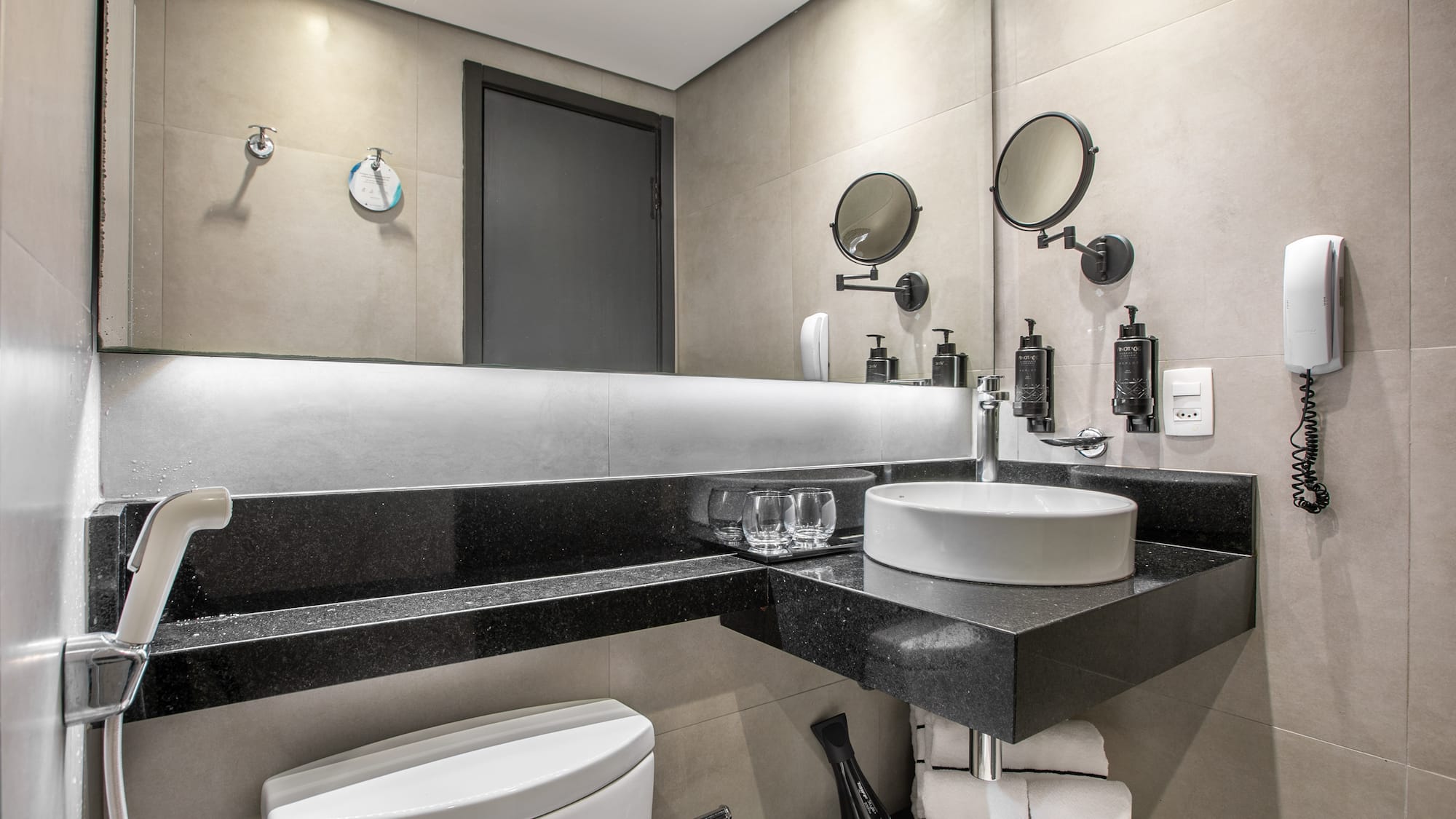 Modern hotel bathroom interior with a white vessel sink, large mirror, and toilet. - Deluxe Room Twin - Meliá Ibirapuera, São Paulo