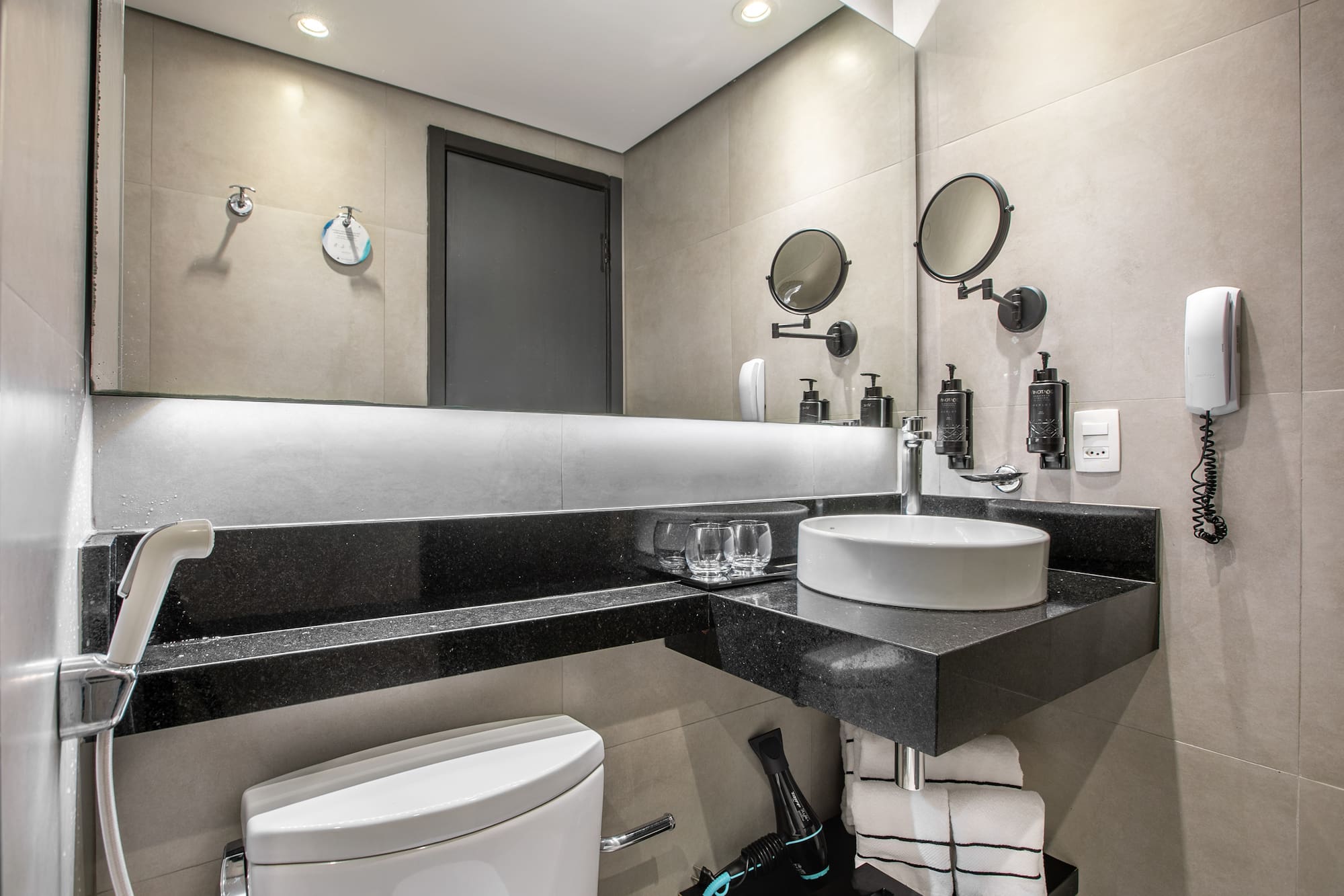 Modern hotel bathroom interior with a white vessel sink, large mirror, and toilet. - Deluxe Room Twin - Meliá Ibirapuera, São Paulo