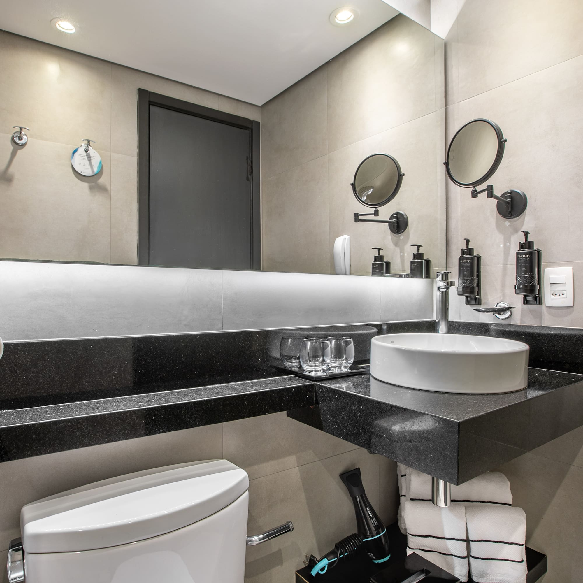 Modern hotel bathroom interior with a white vessel sink, large mirror, and toilet. - Deluxe Room Twin - Meliá Ibirapuera, São Paulo