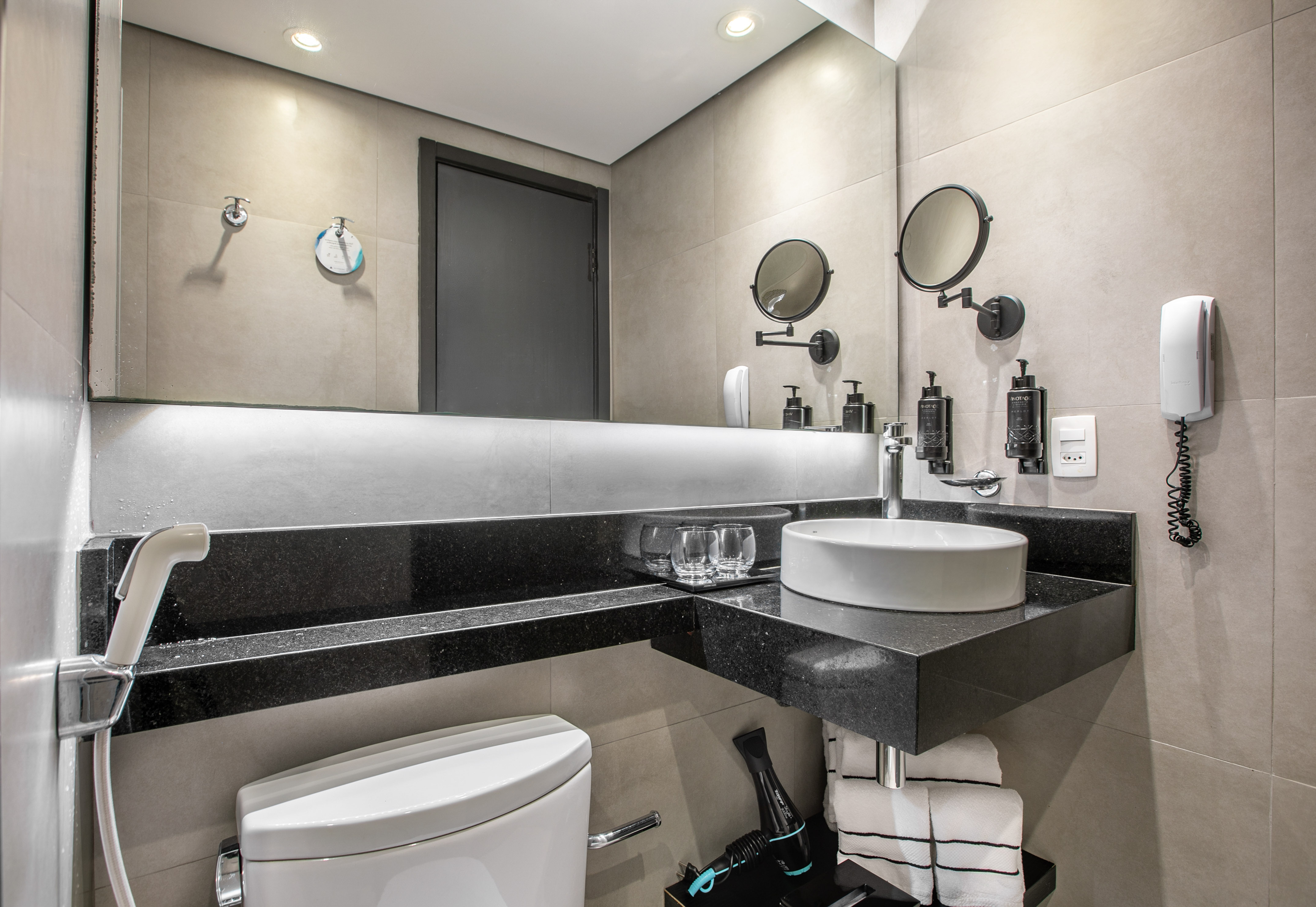 Modern hotel bathroom interior with a white vessel sink, large mirror, and toilet. - Deluxe Room Twin - Meliá Ibirapuera, São Paulo