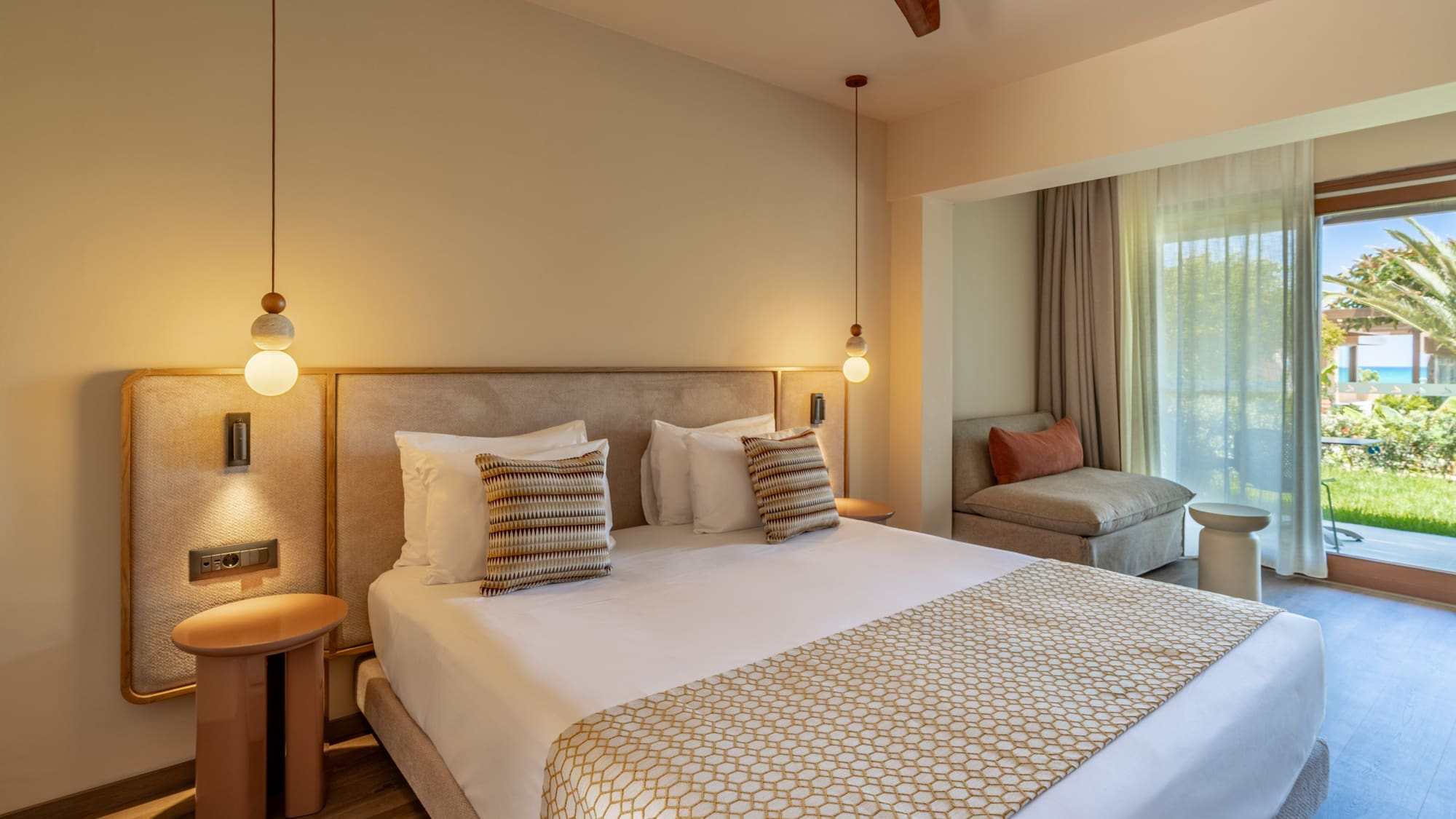 Stylish hotel bedroom with large bed, modern lighting, and balcony sea view.
