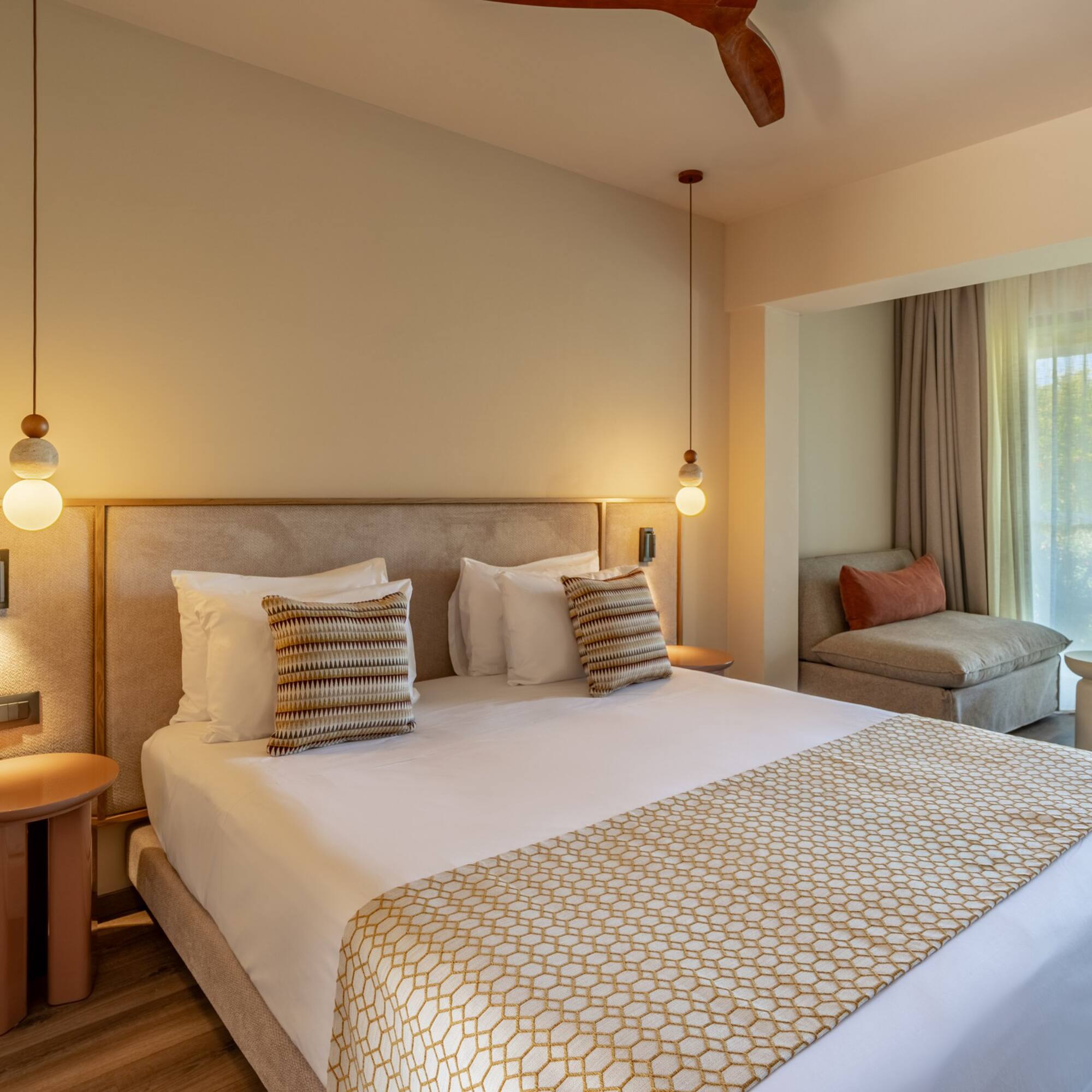 Stylish hotel bedroom with large bed, modern lighting, and balcony sea view.