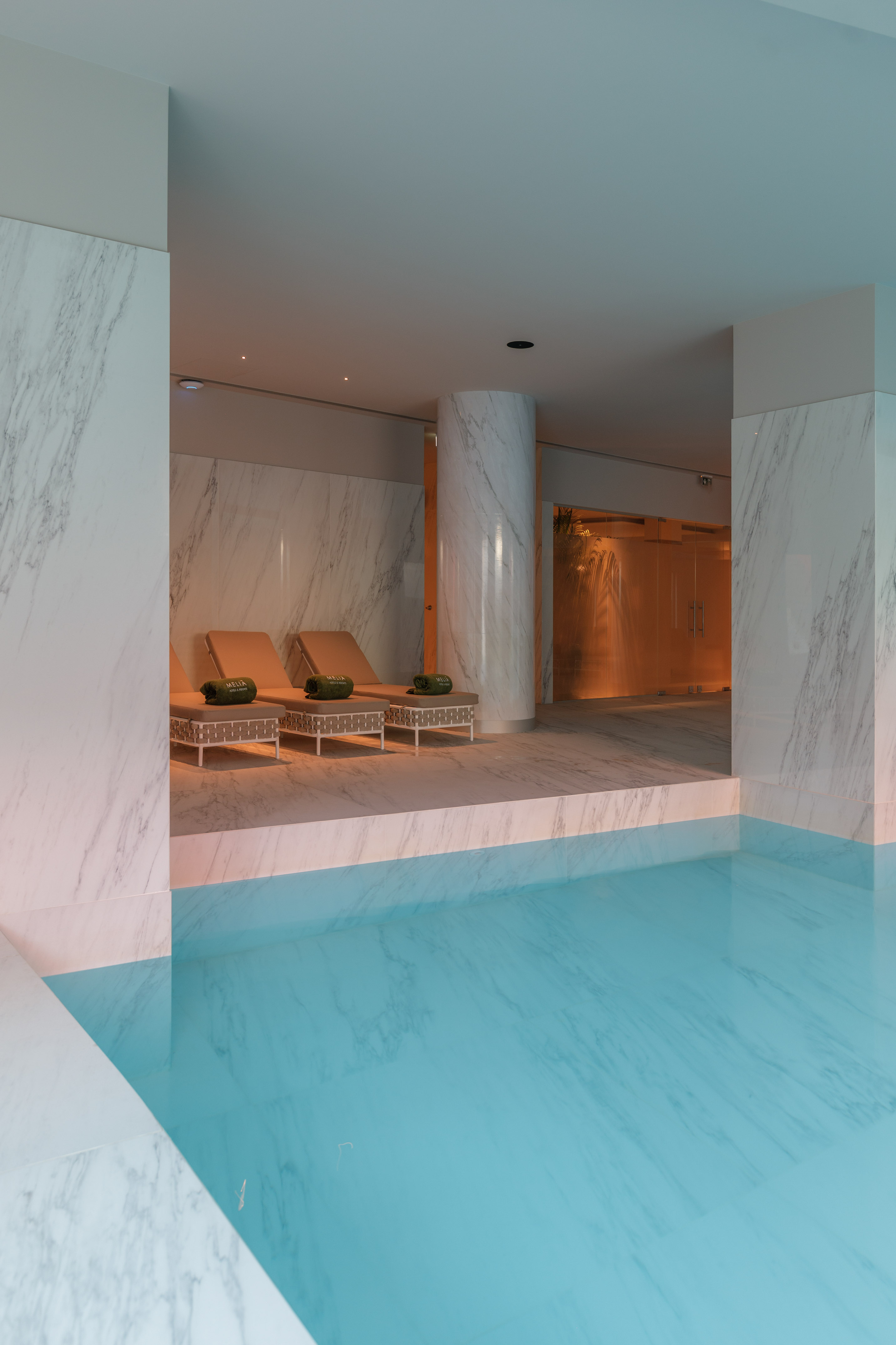 a pool with chairs and a large column