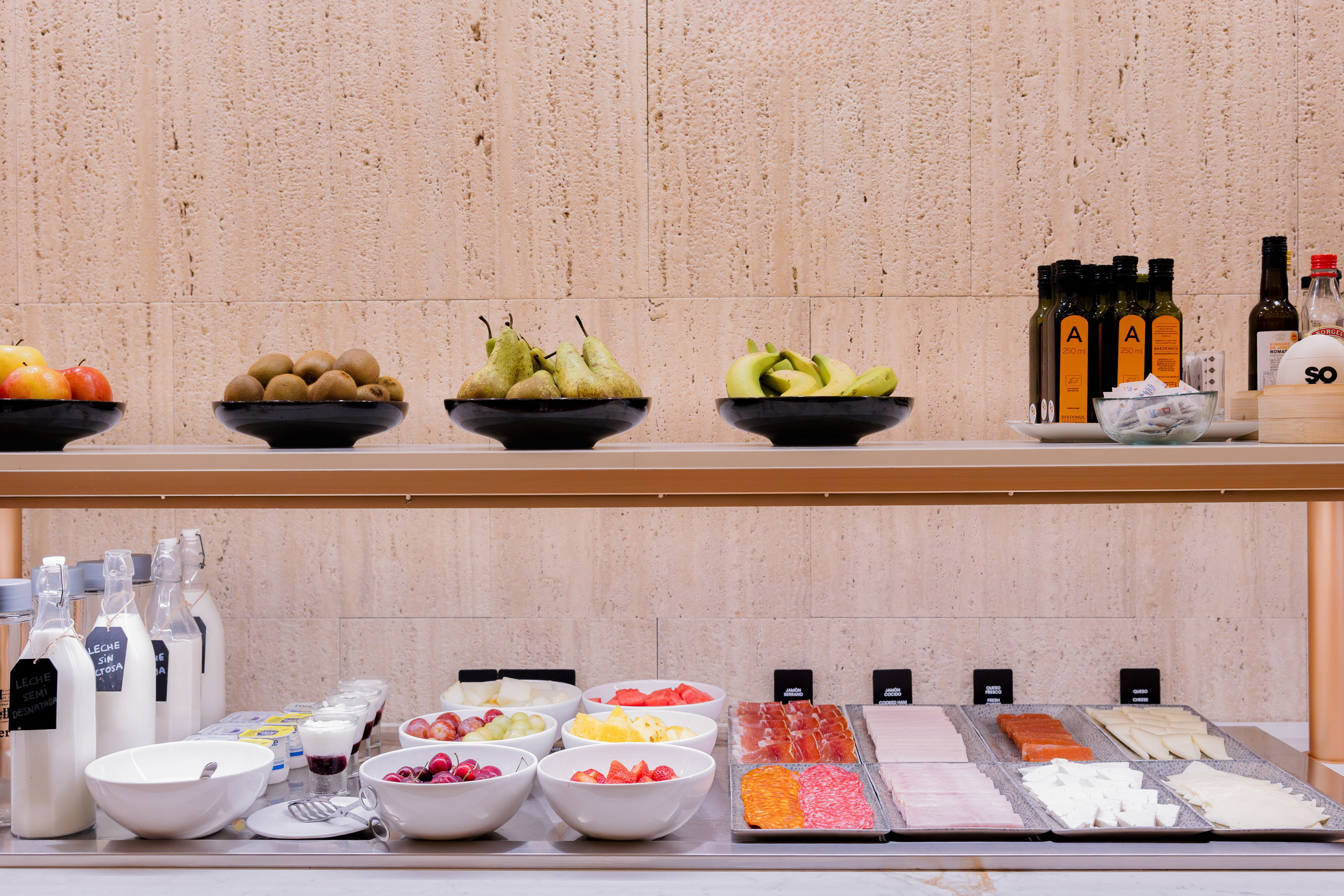 Extensive breakfast buffet with fresh fruit, milk, yogurt, cold cuts, and cheeses.