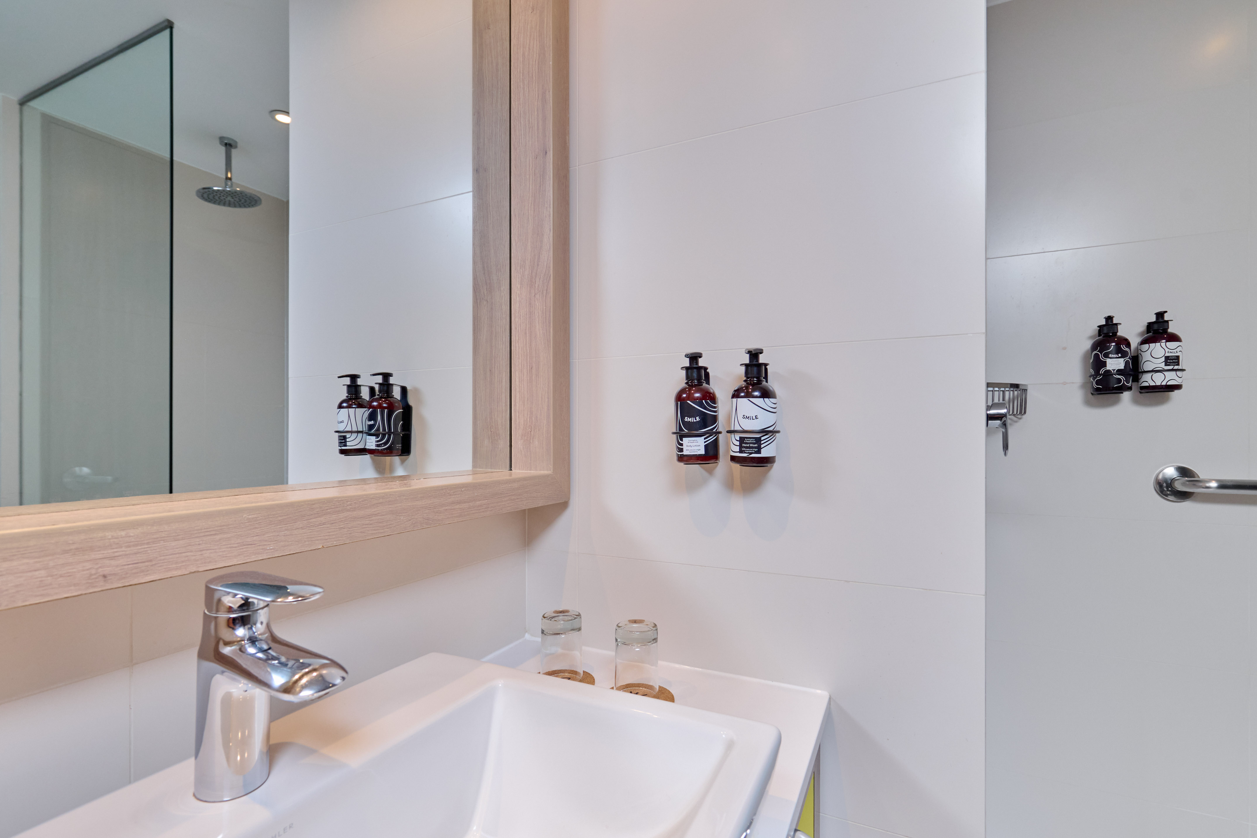Modern bathroom sink, chrome faucet, mirror, and wall-mounted toiletries.