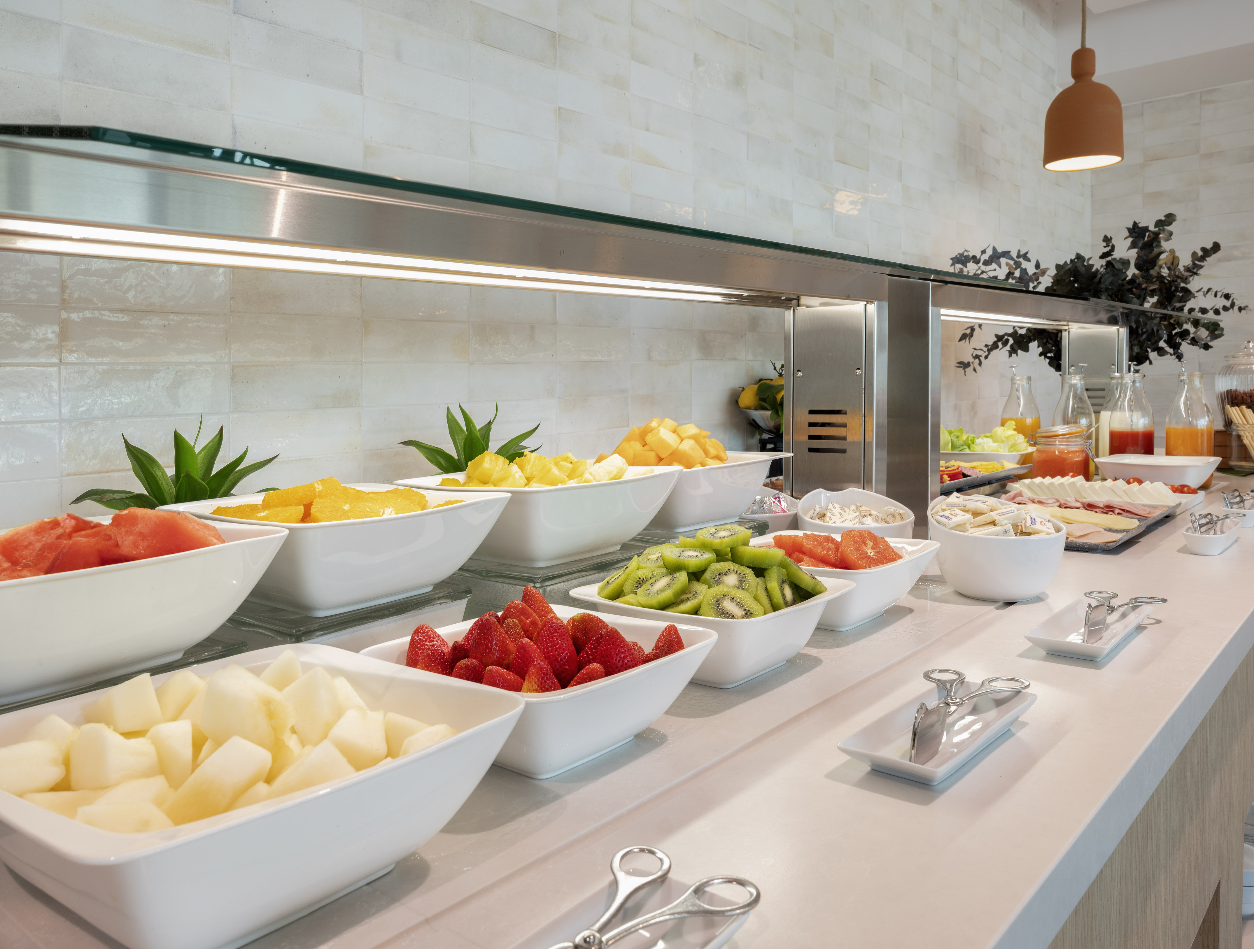 Breakfast buffet with fresh fruit, cold cuts, and juices.