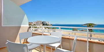 a table and chairs on a balcony overlooking a beach