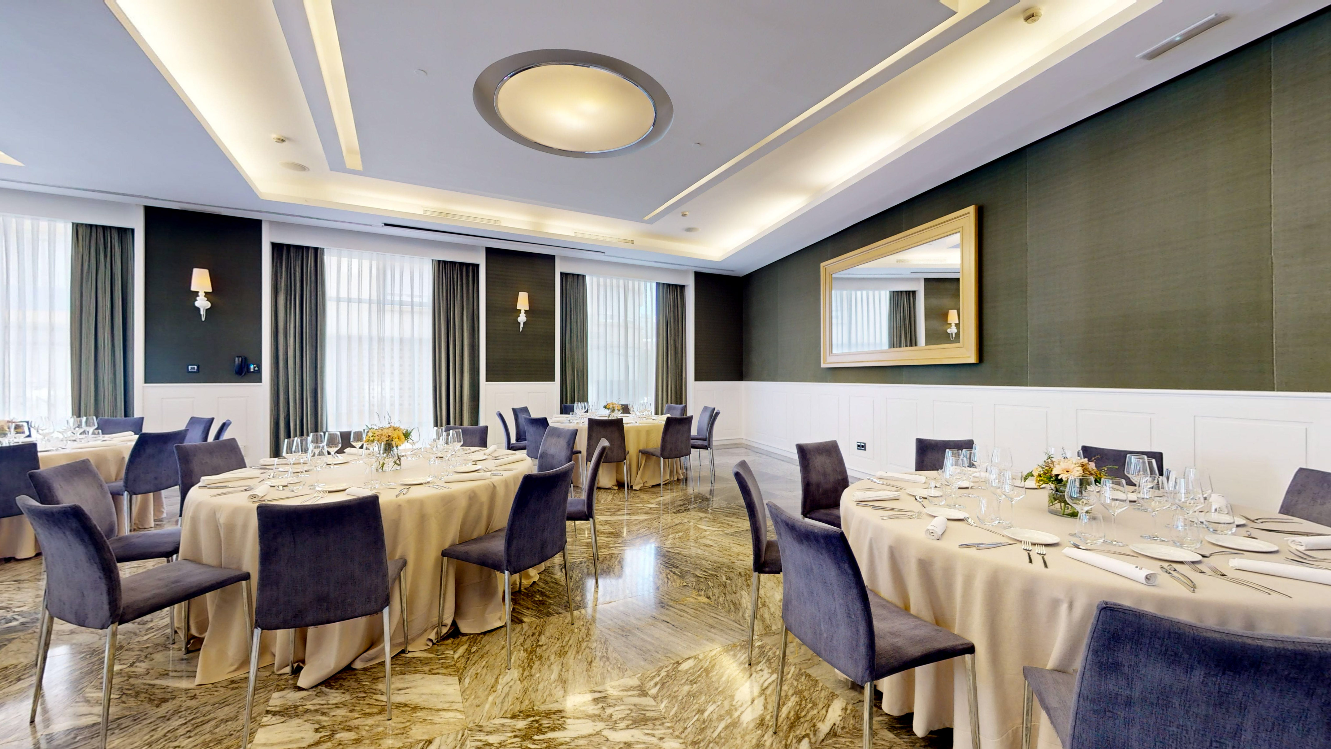 Elegant event dining room with round tables, velvet chairs, and luxury decor.