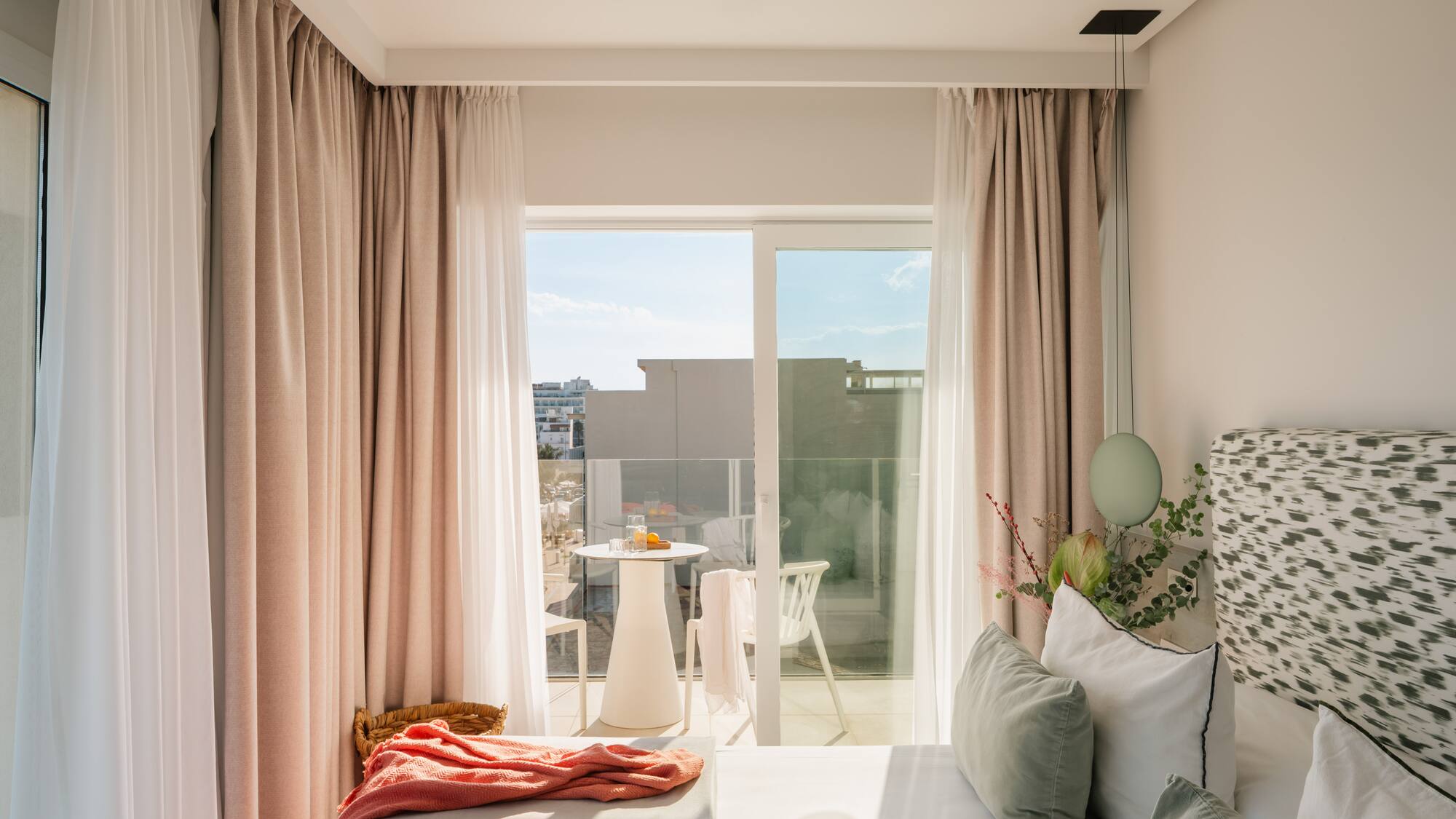 a bed with pink curtains and a table with plants and a table with a balcony