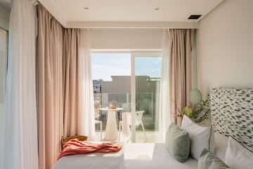 a bed with pink curtains and a table with plants and a table with a balcony