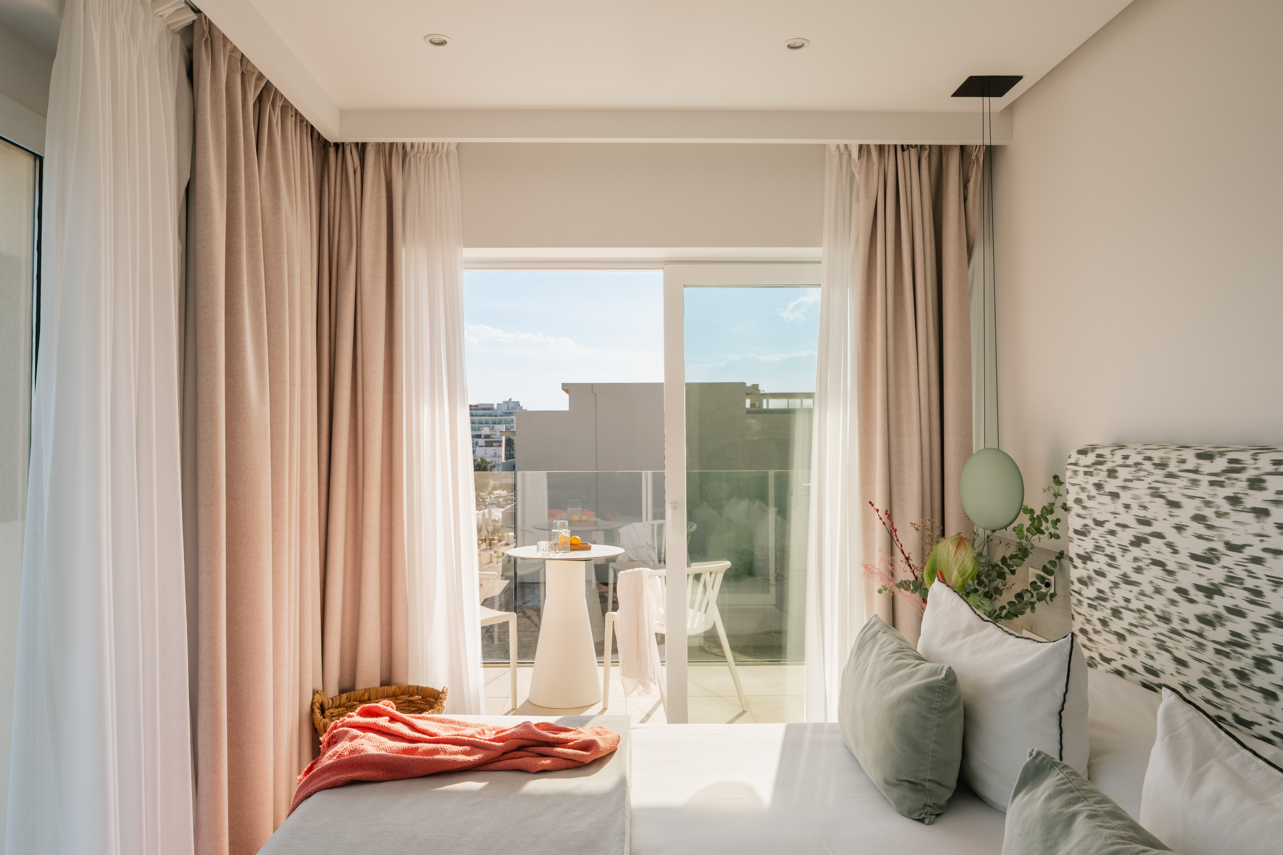 a bed with pink curtains and a table with plants and a table with a balcony