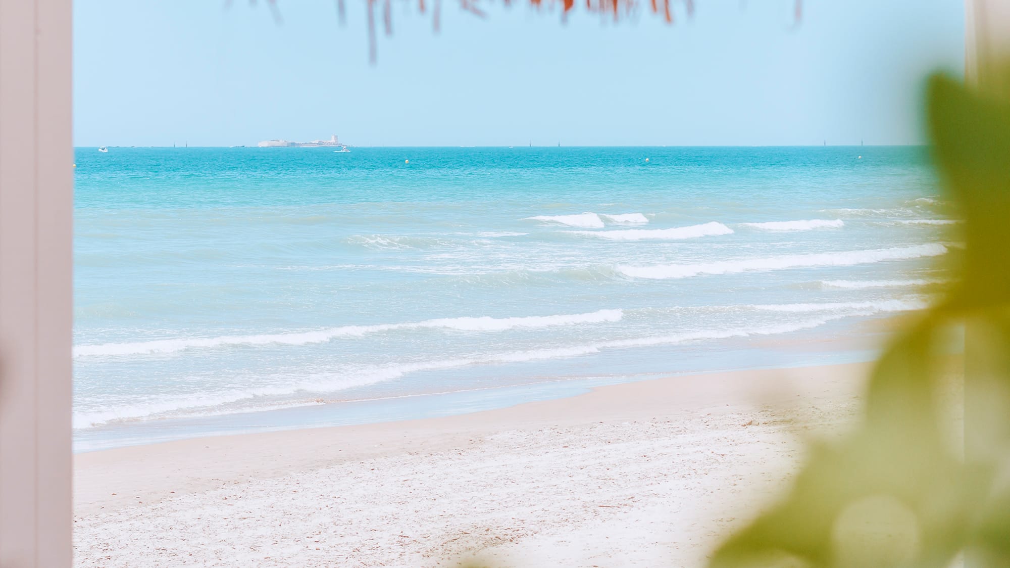 a beach with a straw umbrella and a blue ocean