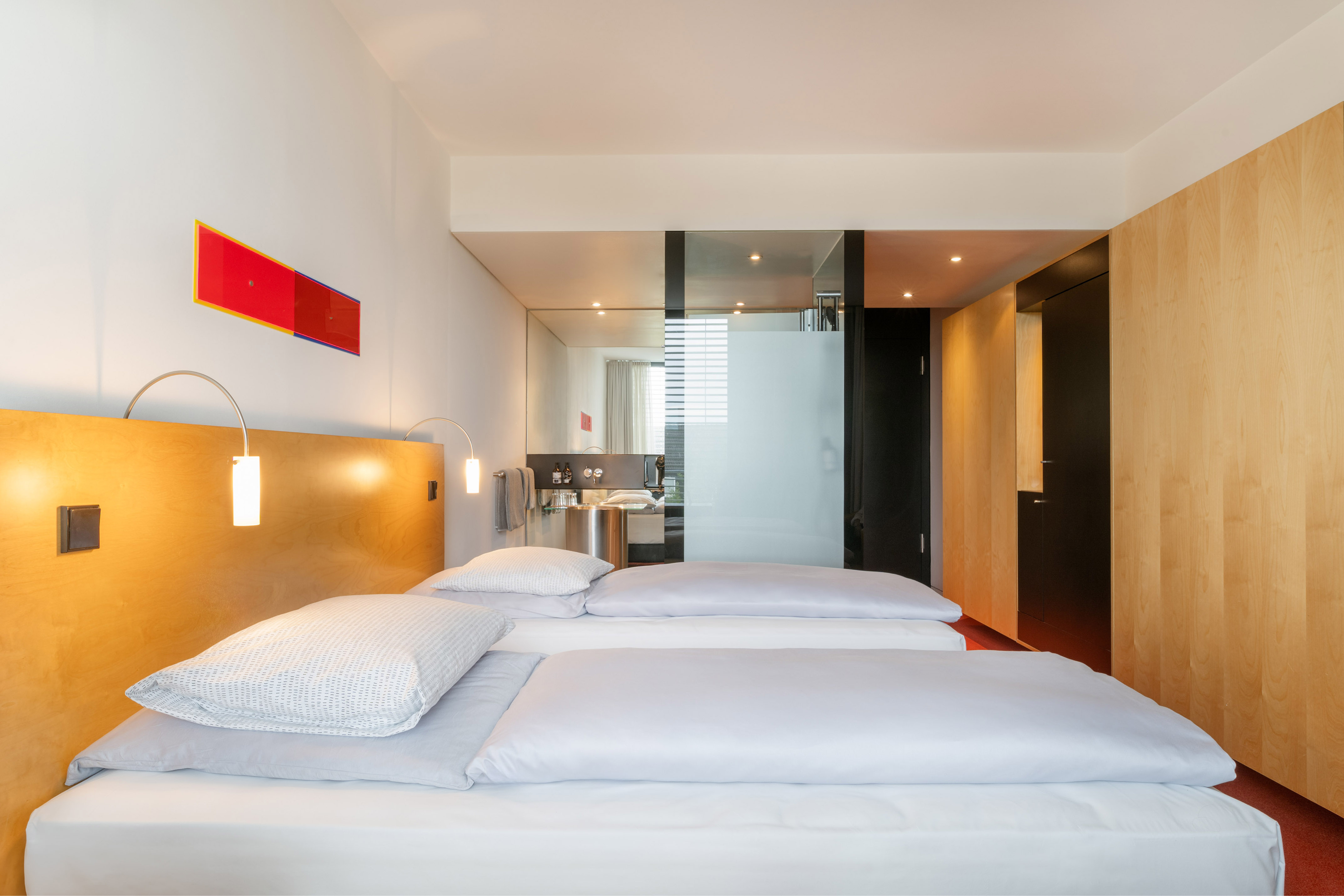 Minimalist hotel room with twin beds, wooden headboard, and glass bathroom. - The INNSiDE Twin Room - INNSiDE Düsseldorf Seestern, Düsseldorf