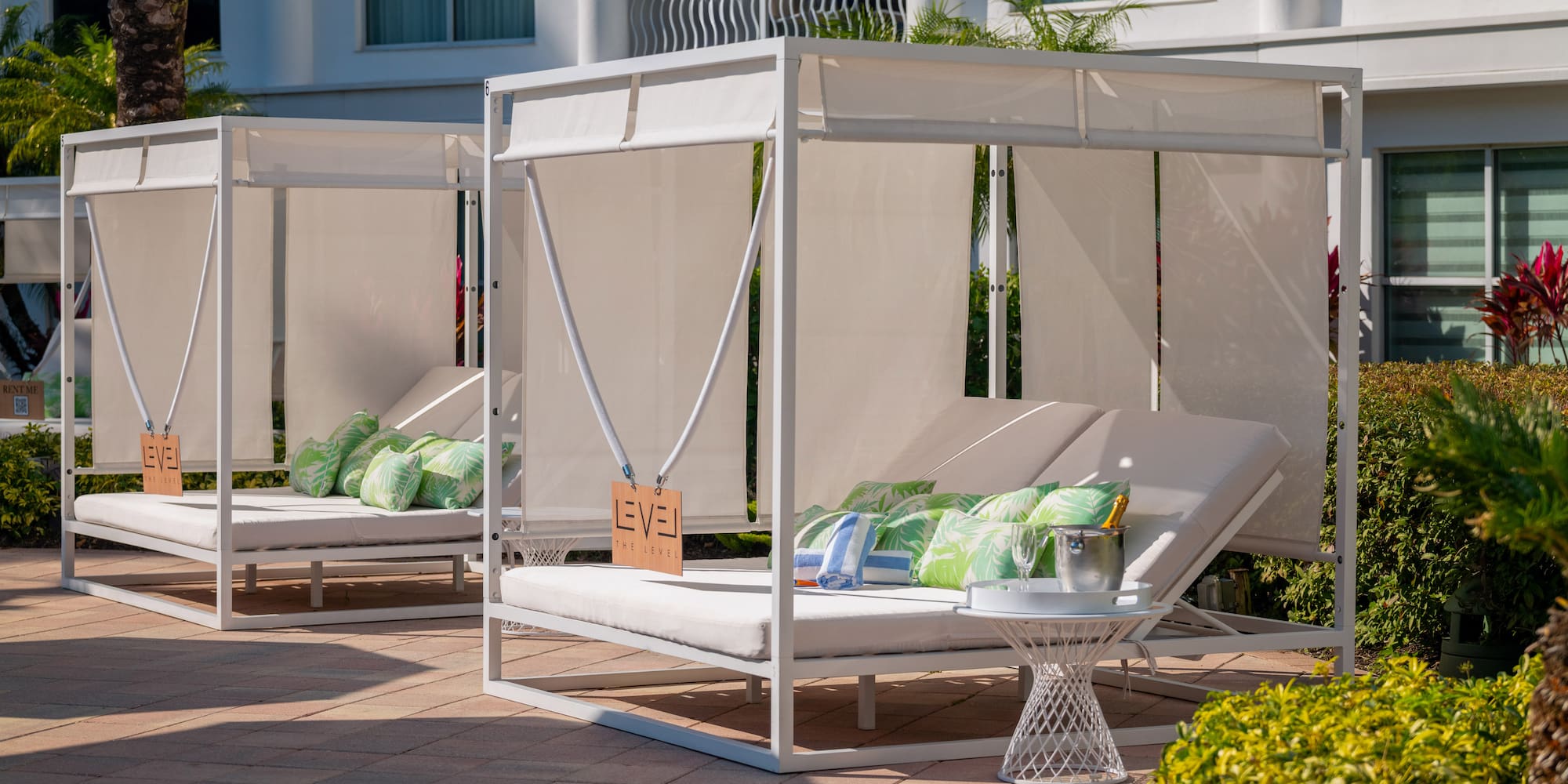 a white canopy bed with pillows on a patio