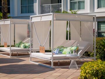 a white canopy bed with pillows on a patio