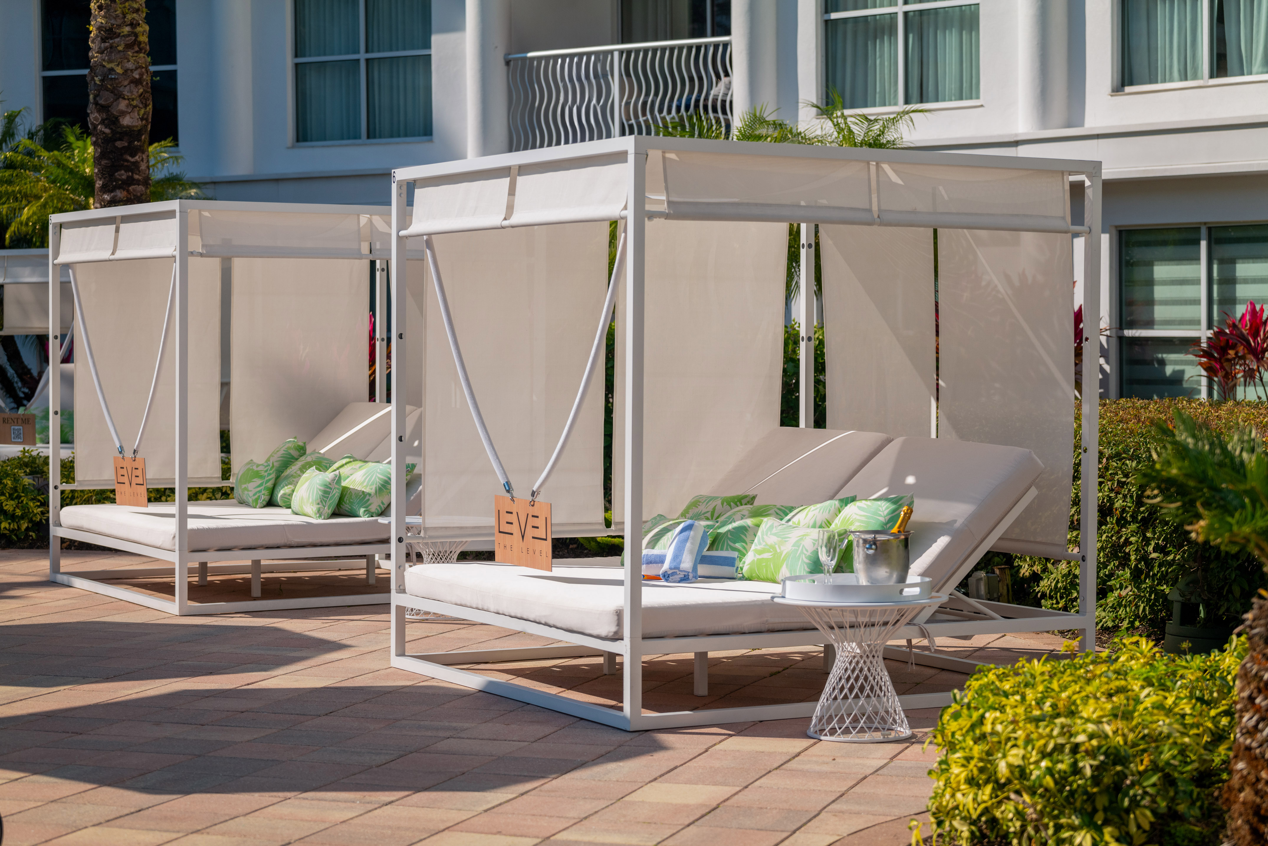 Luxury white outdoor cabanas on a hotel patio, green pillows and champagne.