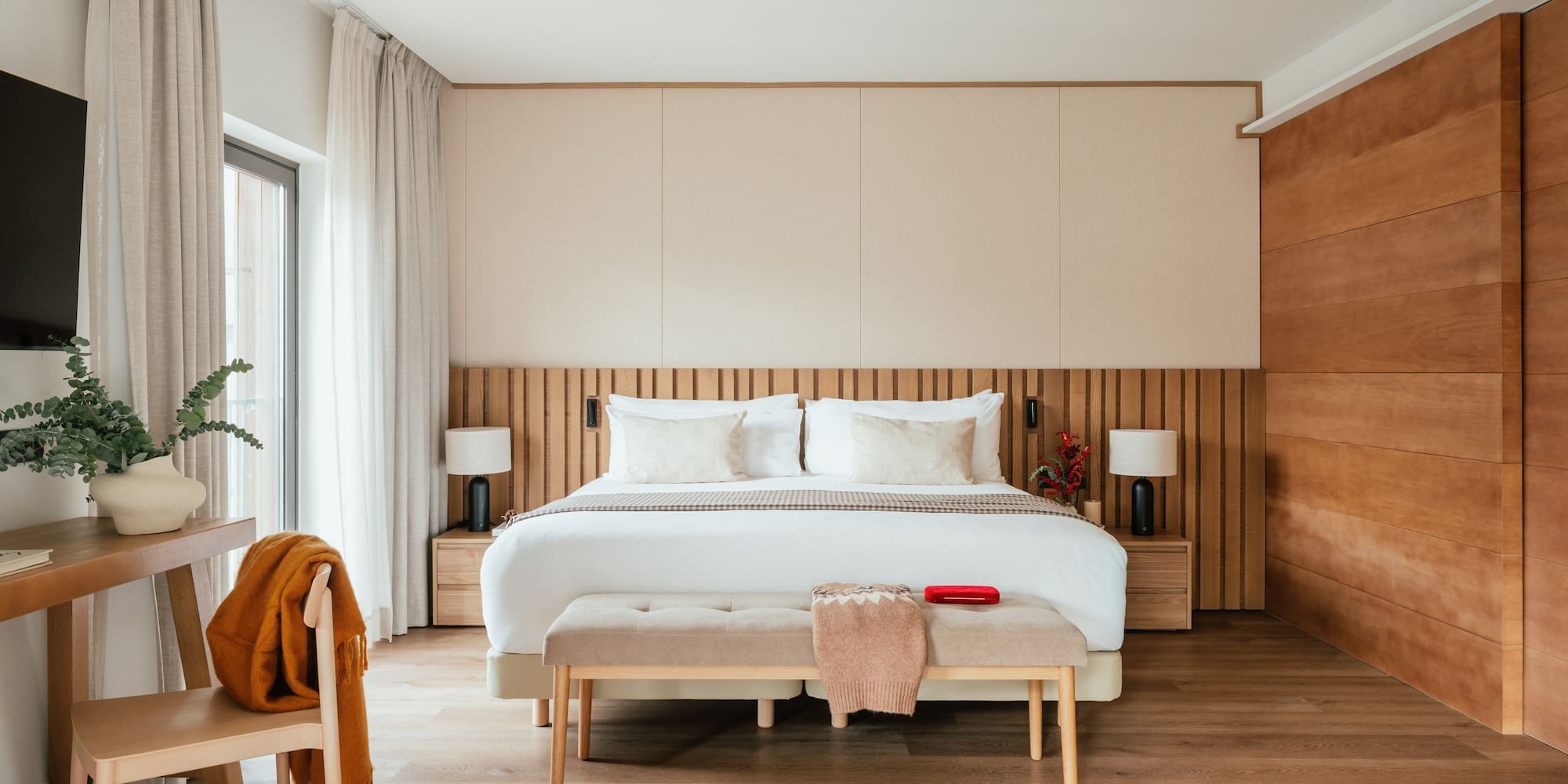 Contemporary bedroom with king bed, wooden slat headboard, and neutral decor.