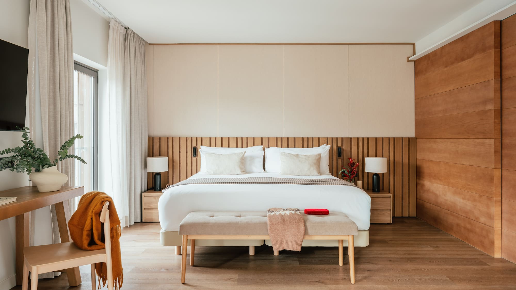 Contemporary bedroom with king bed, wooden slat headboard, and neutral decor.