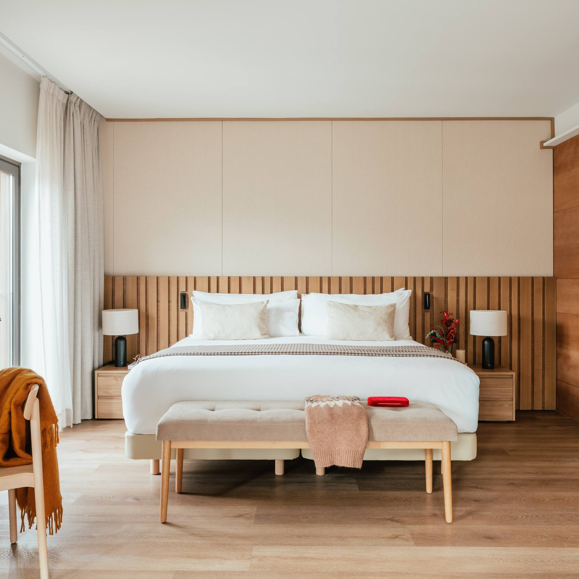 Contemporary bedroom with king bed, wooden slat headboard, and neutral decor.