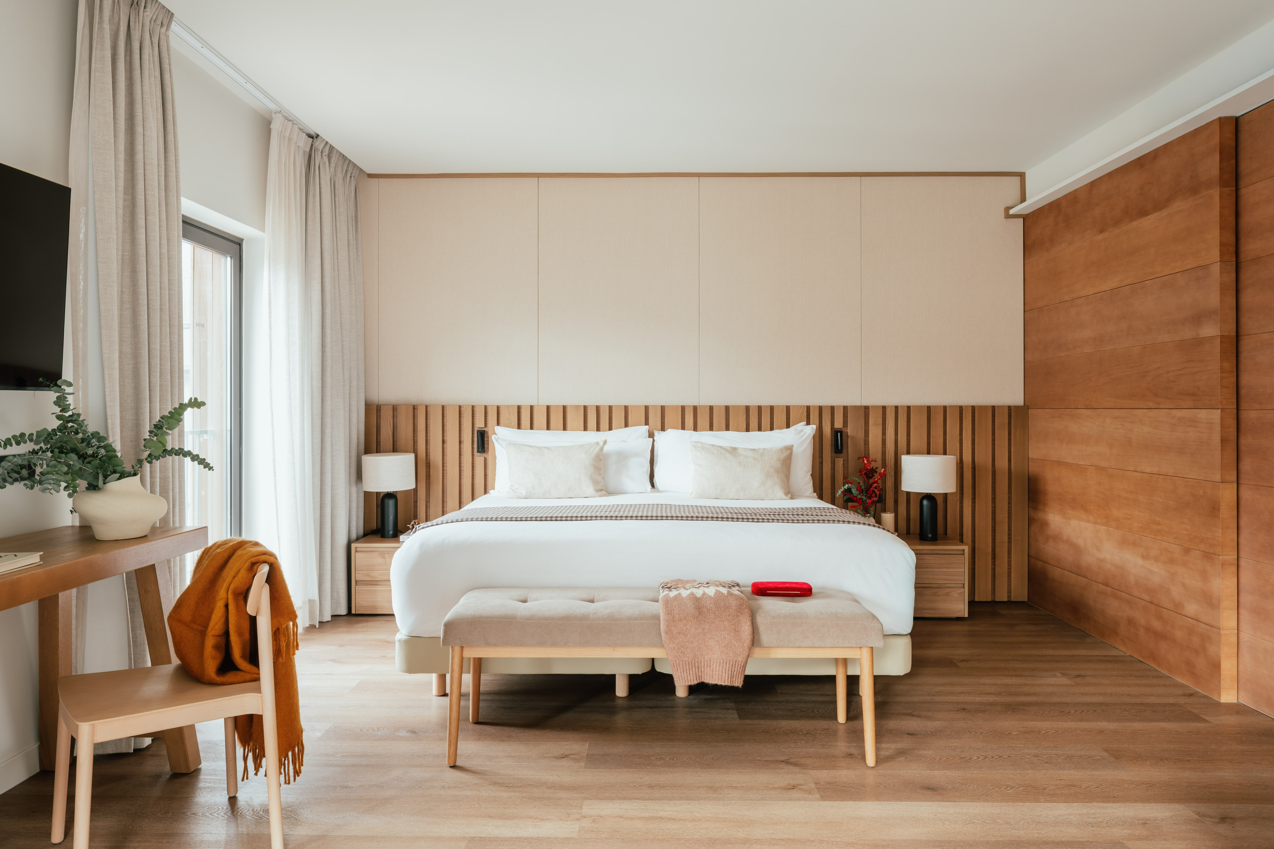Contemporary bedroom with king bed, wooden slat headboard, and neutral decor.