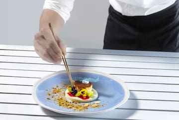 a person holding chopsticks to a plate of food