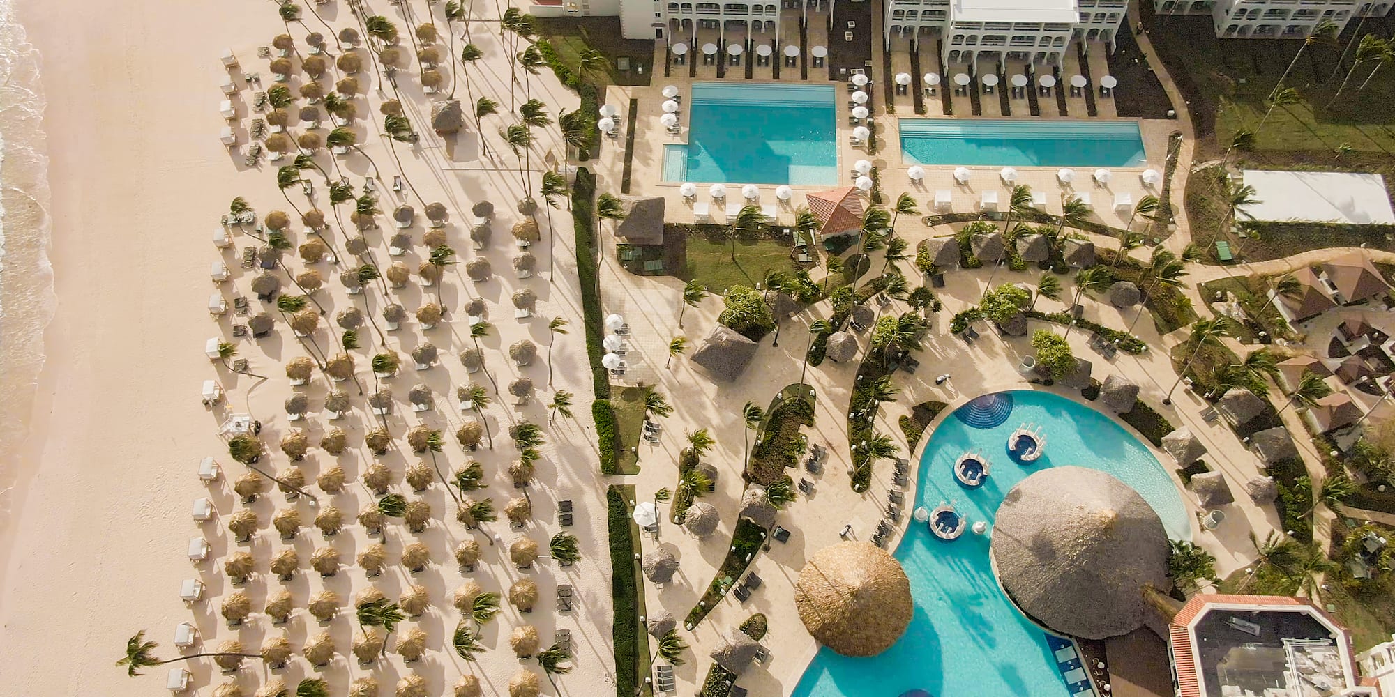 a pool and a building with straw umbrellas