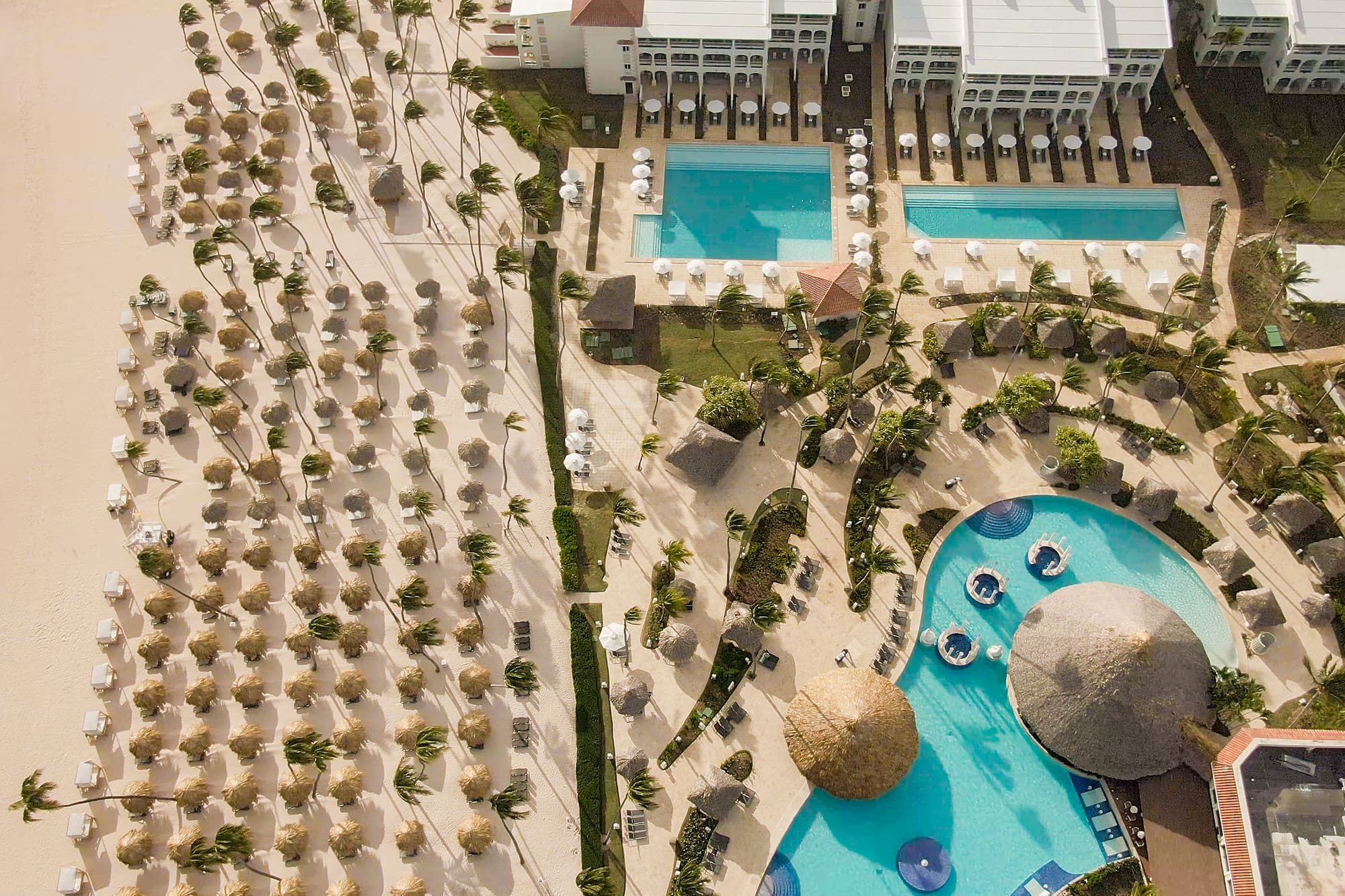 a pool and a building with straw umbrellas