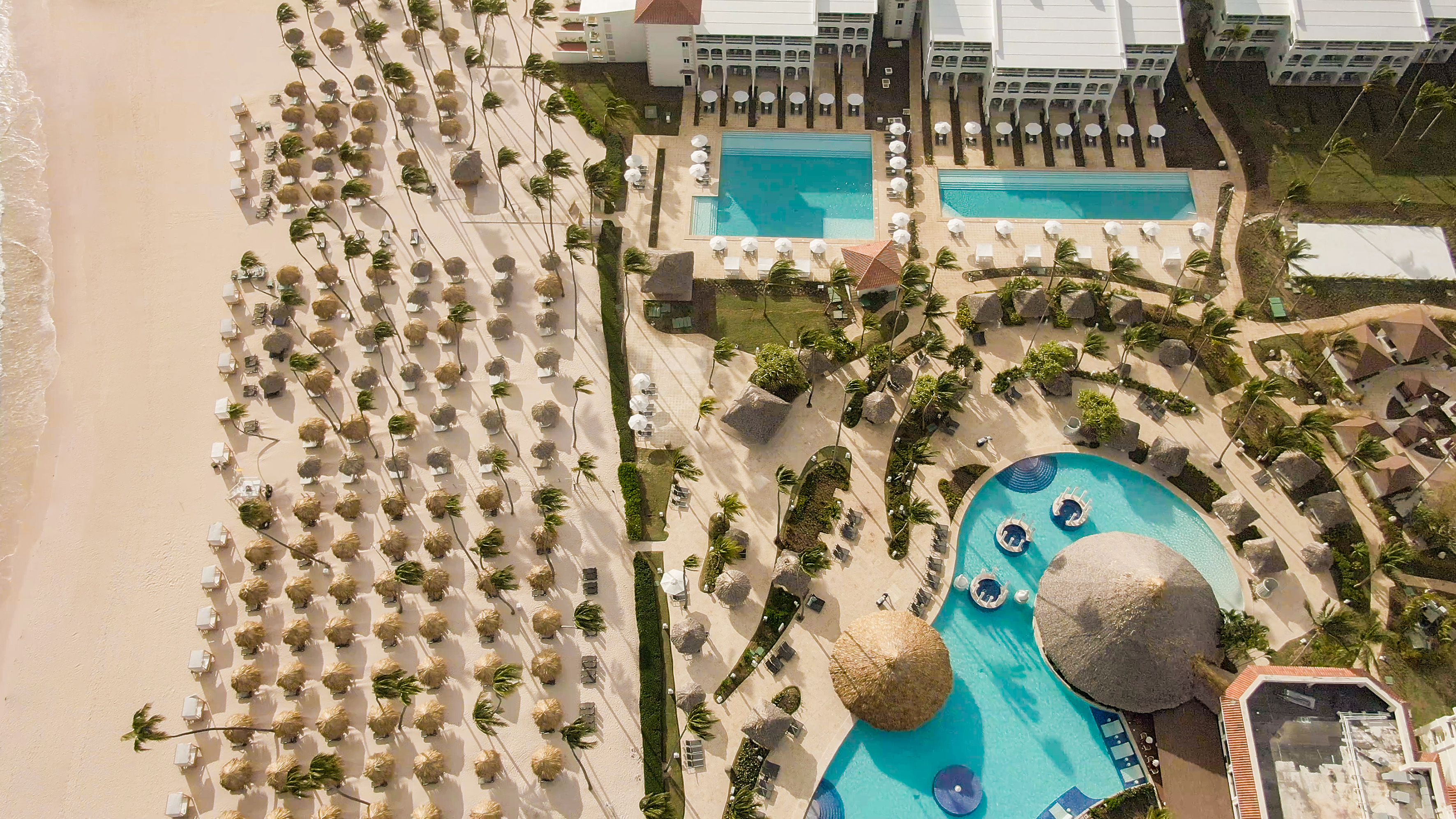 a pool and a building with straw umbrellas