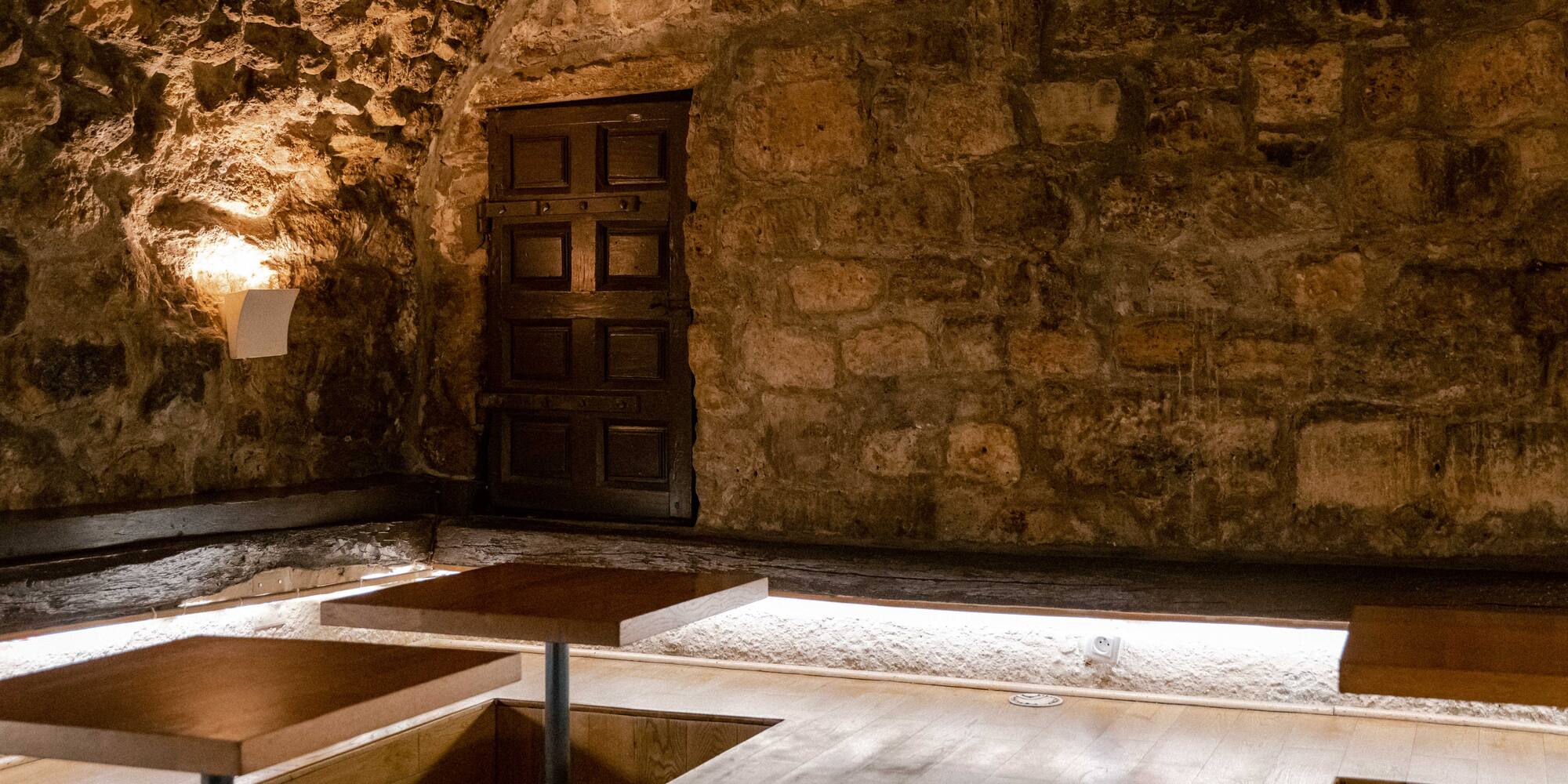 a room with a stone wall and wooden tables