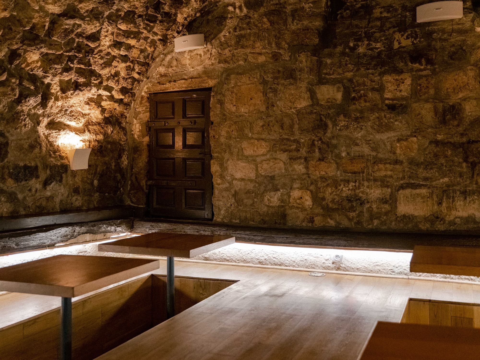 a room with a stone wall and wooden tables